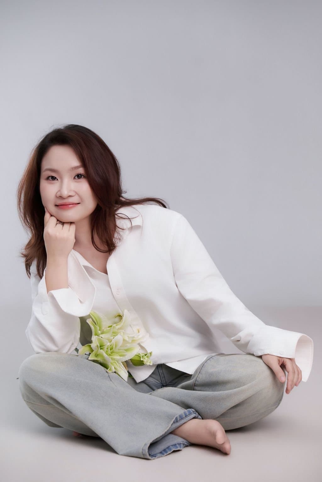 Người mẹ tuổi ba mươi ba ngồi nhẹ nhàng với hoa nhỏ trên tay