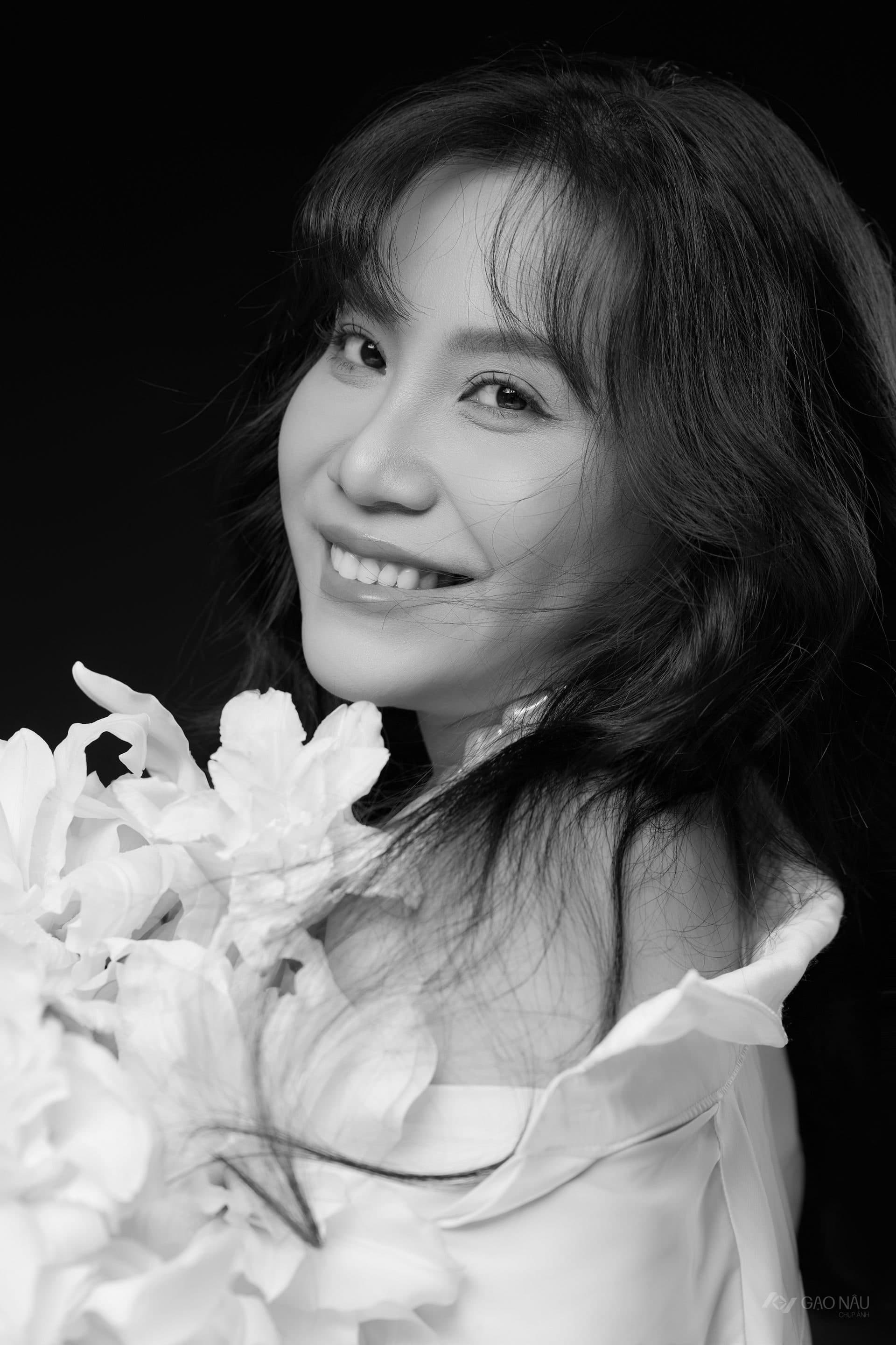 Đen trắng, chị cười tươi tự nhiên, ôm bó hoa lily trắng