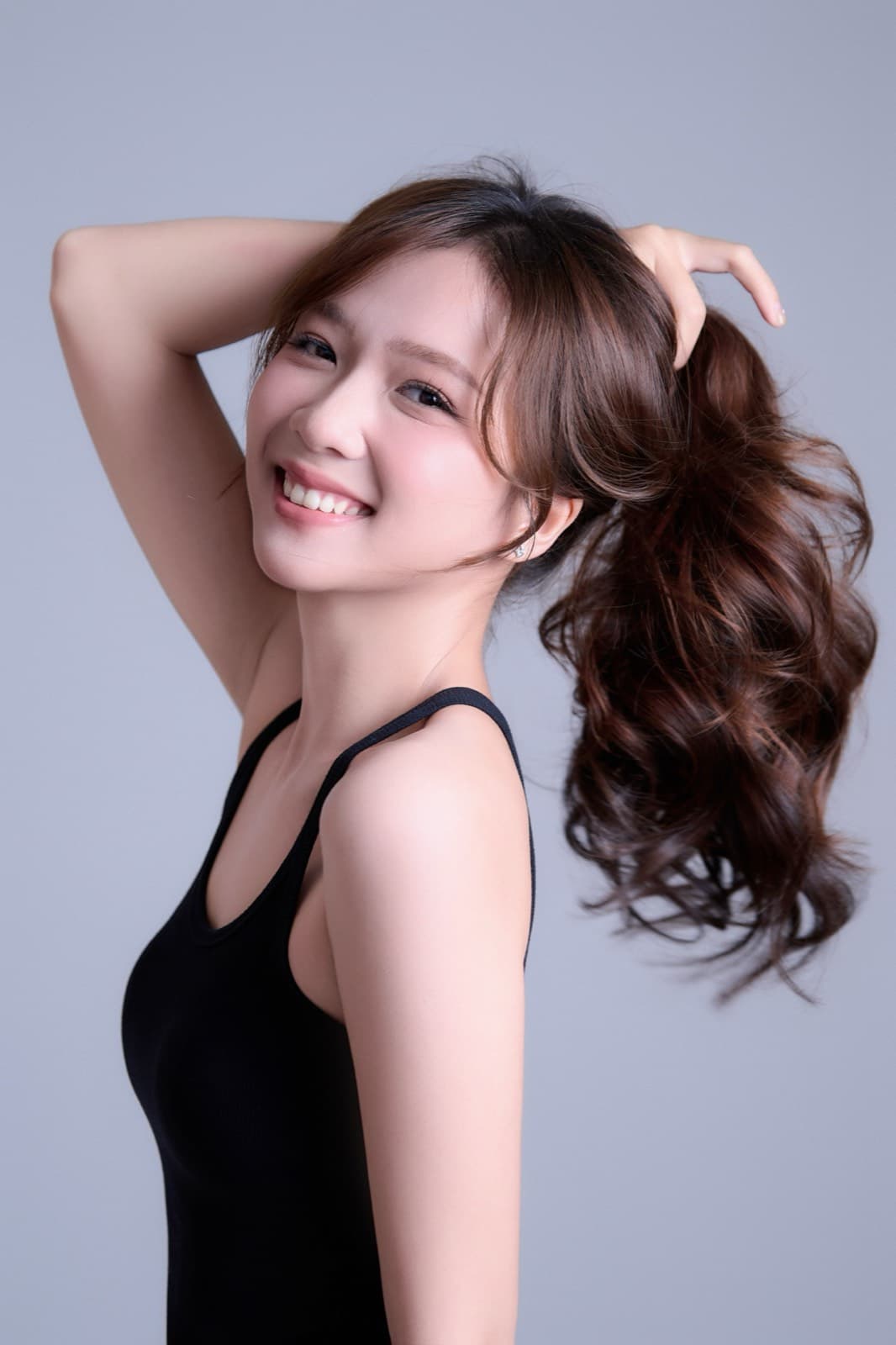 Sắc Ly cười rạng rỡ, tóc cột cao bay nhẹ trong gió, vai trần áo tank top đen.