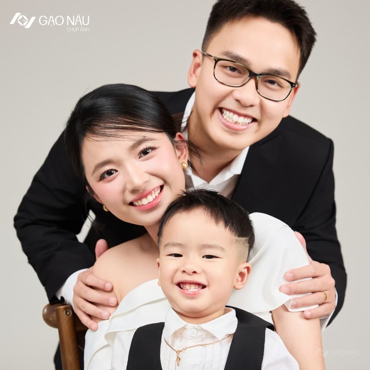 Ba đeo kính đen ôm mẹ và con trai nhỏ trong studio, cả ba cùng cười rạng rỡ