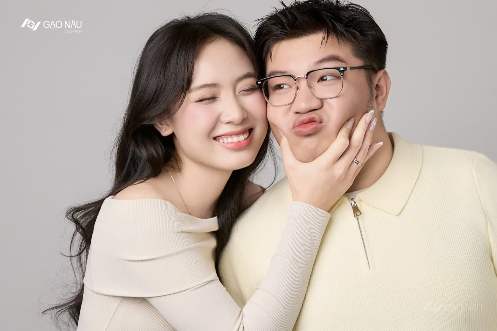 Một cô ôm đầu người yêu, đặt tay lên má anh, cả hai cùng cười tự nhiên