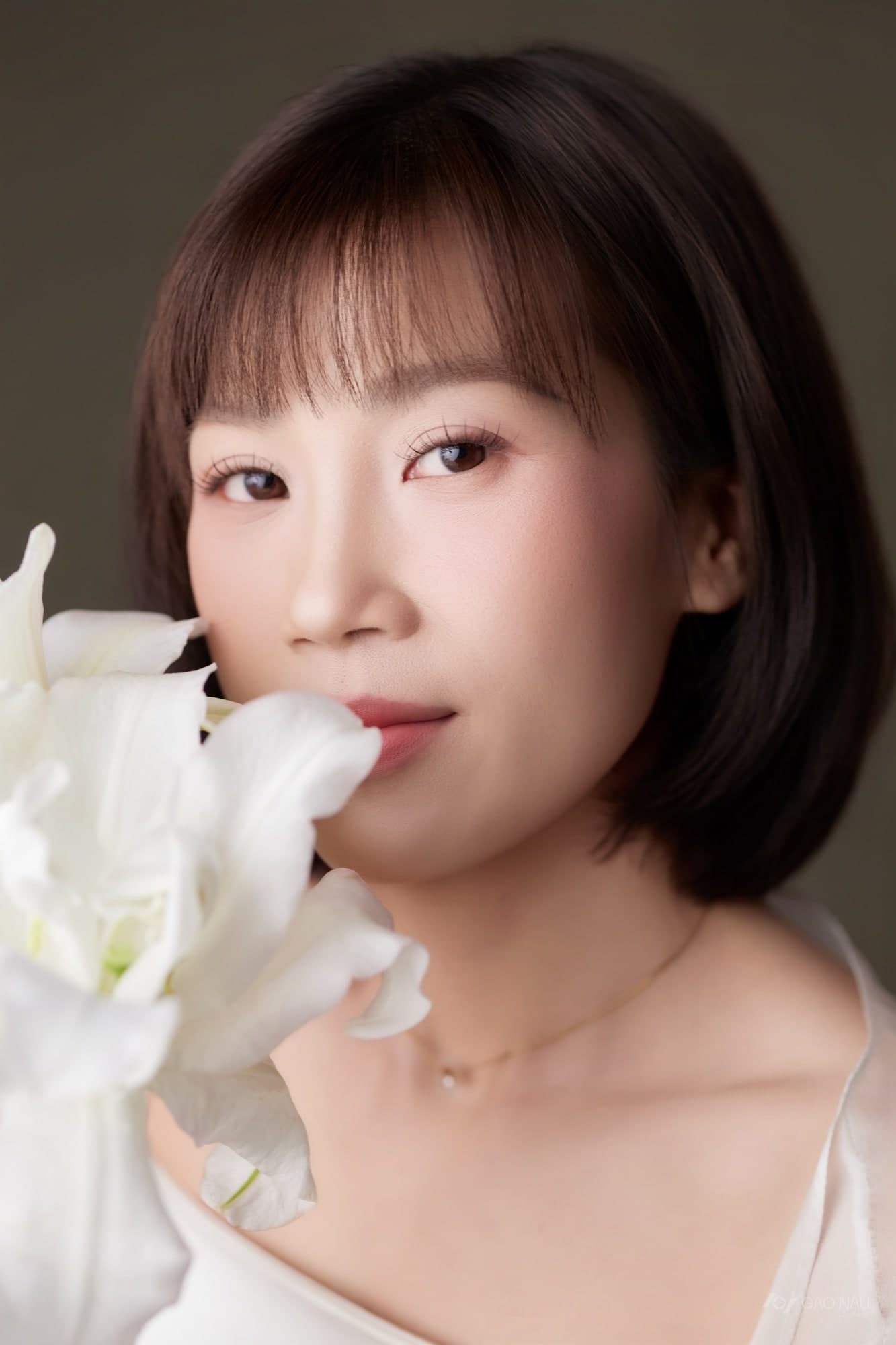 Chị Vy Mi cận mặt, tay đưa cánh hoa gần môi, mắt nhắm nhẹ
