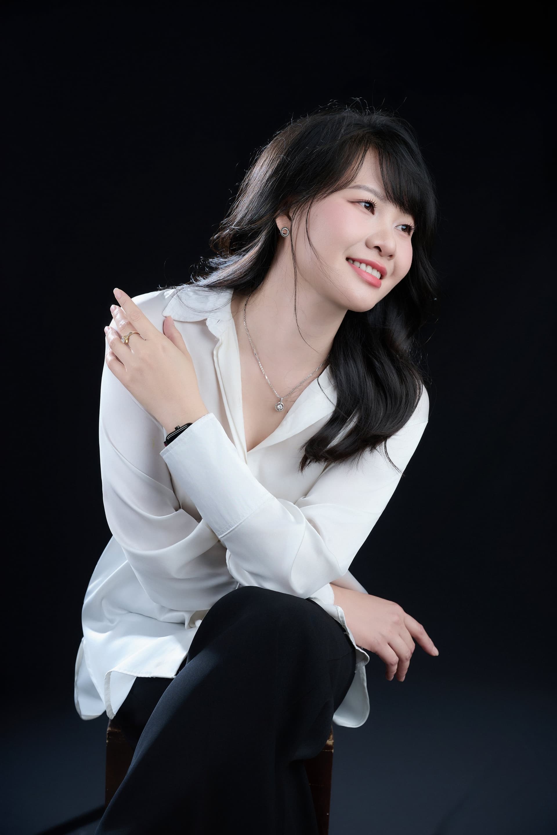 Ngọc Huyền ngồi nghiêng, áo trắng, tay đeo đồng hồ đen, ngón tay đeo nhẫn vàng — những chi tiết nhỏ của một đời sống đã tám năm.