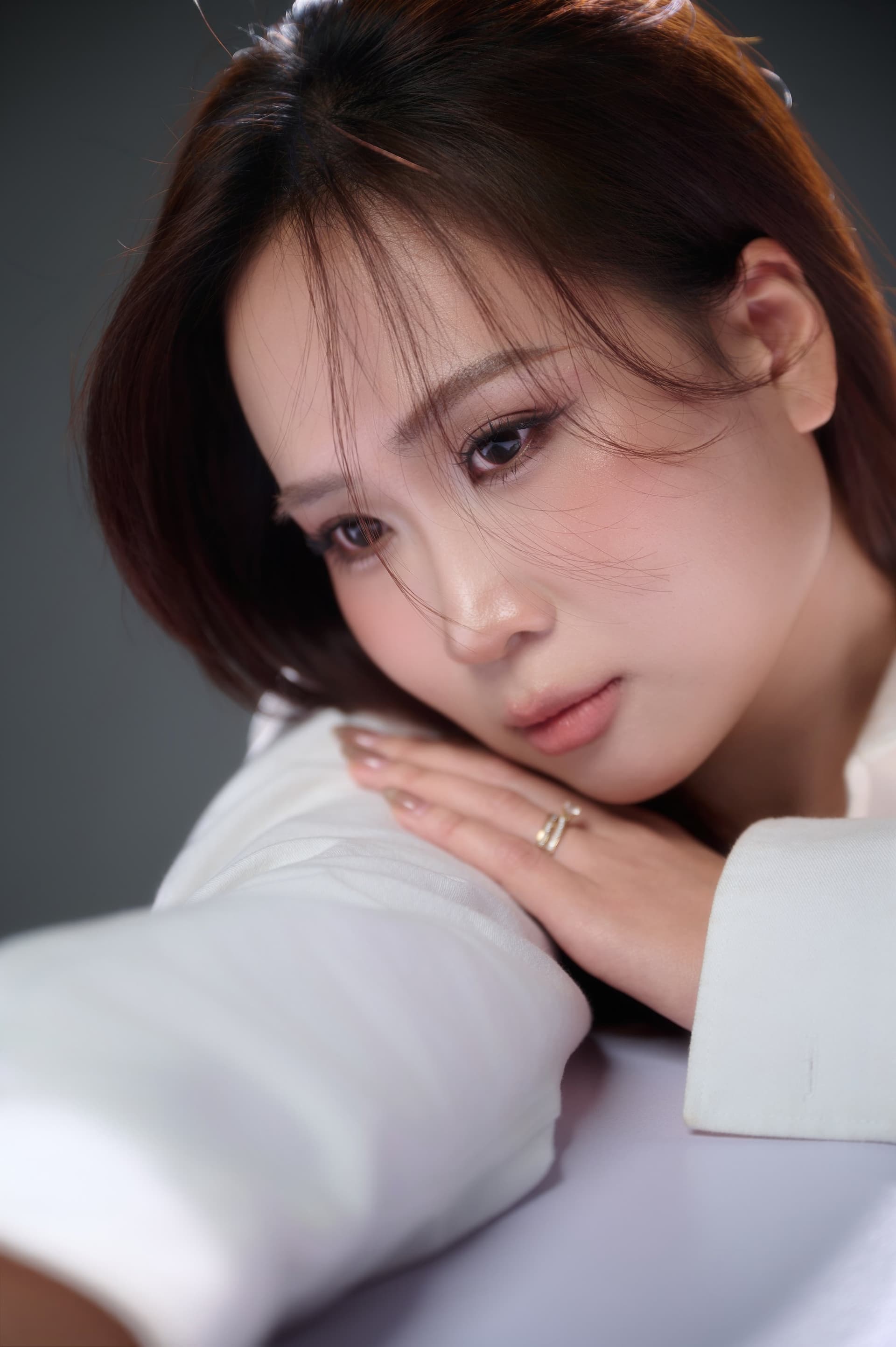 Người phụ nữ nghiêng đầu, tay đỡ má, ánh nhìn xa xăm — khoảng trống nhỏ khi người thường đứng sau vắng mặt