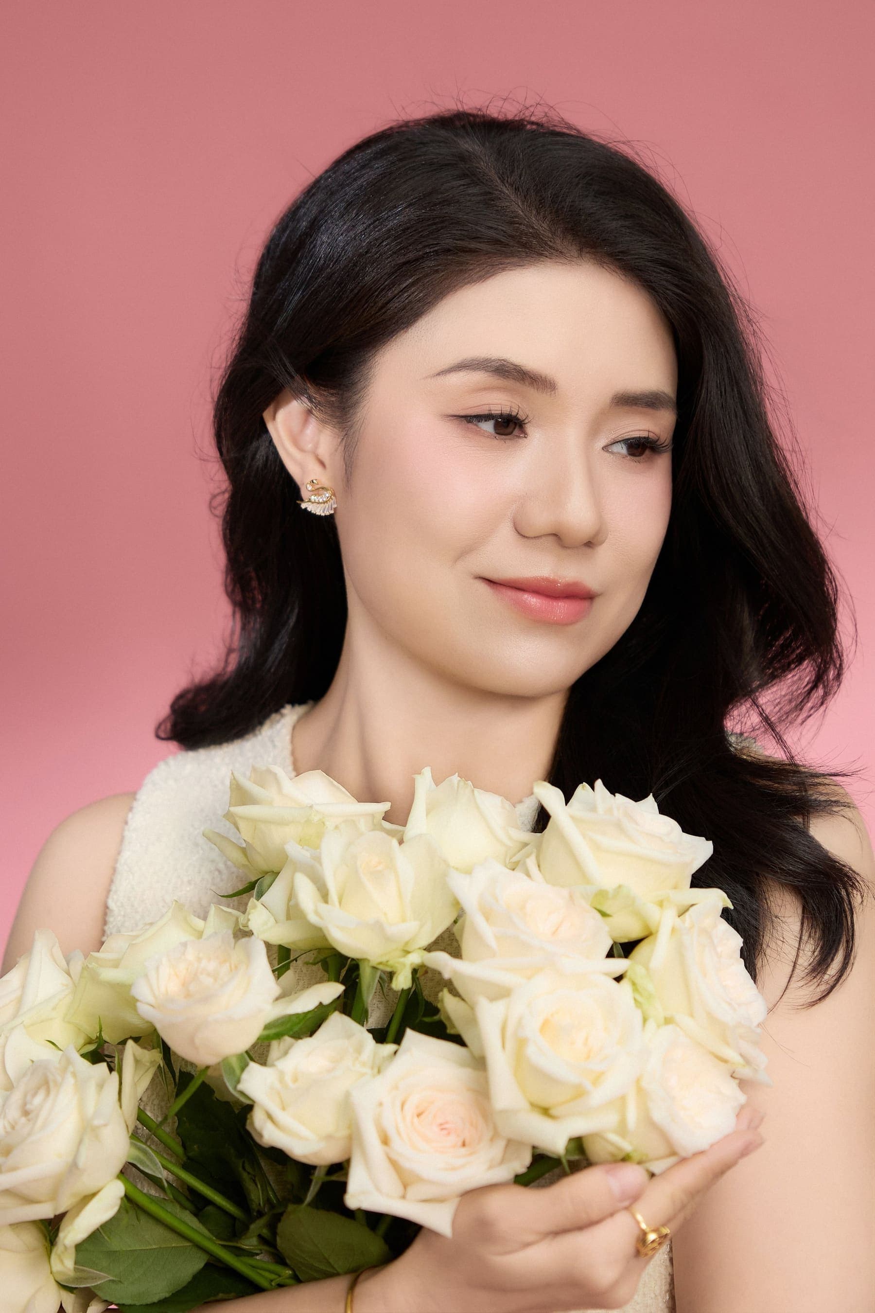 Ngọc Xinh áo trắng ôm bó hoa hồng trắng cuống dài, gương mặt sáng nhẹ, một mốc ba mươi bảy tuổi giữ lại cho mình