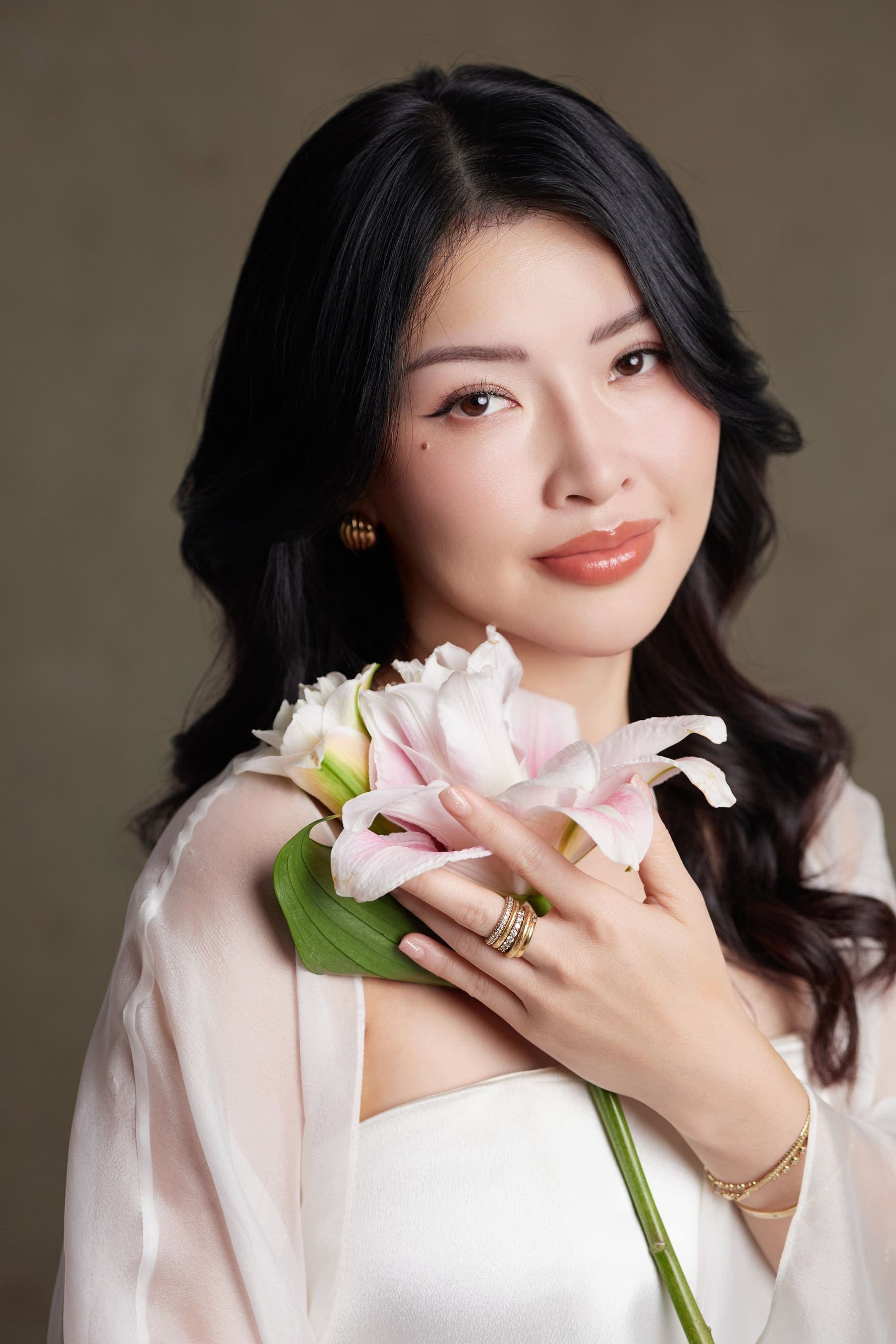 Trang trong áo trắng dáng dài, tay ôm một cành hoa hồng nhỏ, ánh mắt nghiêng — một ngày của riêng mình