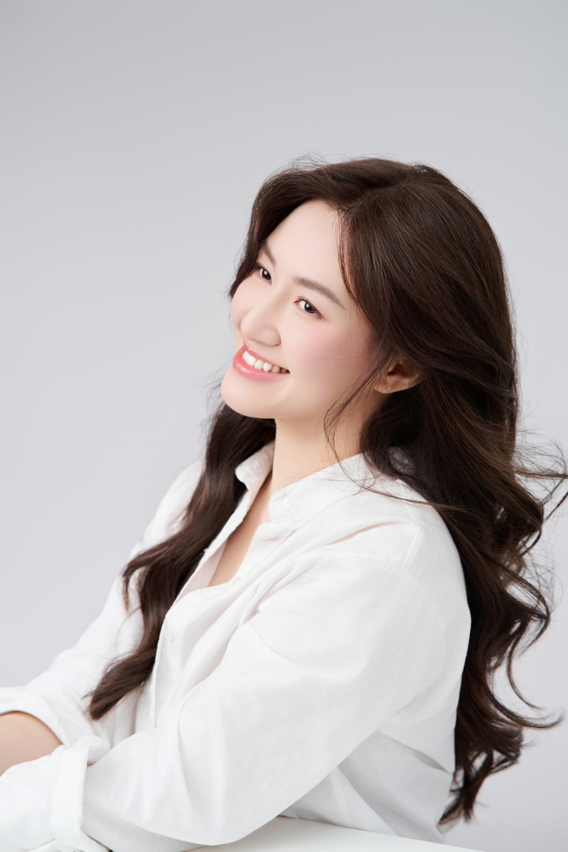 Chị Vân Võ trong chiếc áo sơ mi trắng, nhìn nghiêng qua vai với nụ cười dịu nhẹ dưới ánh sáng tự nhiên