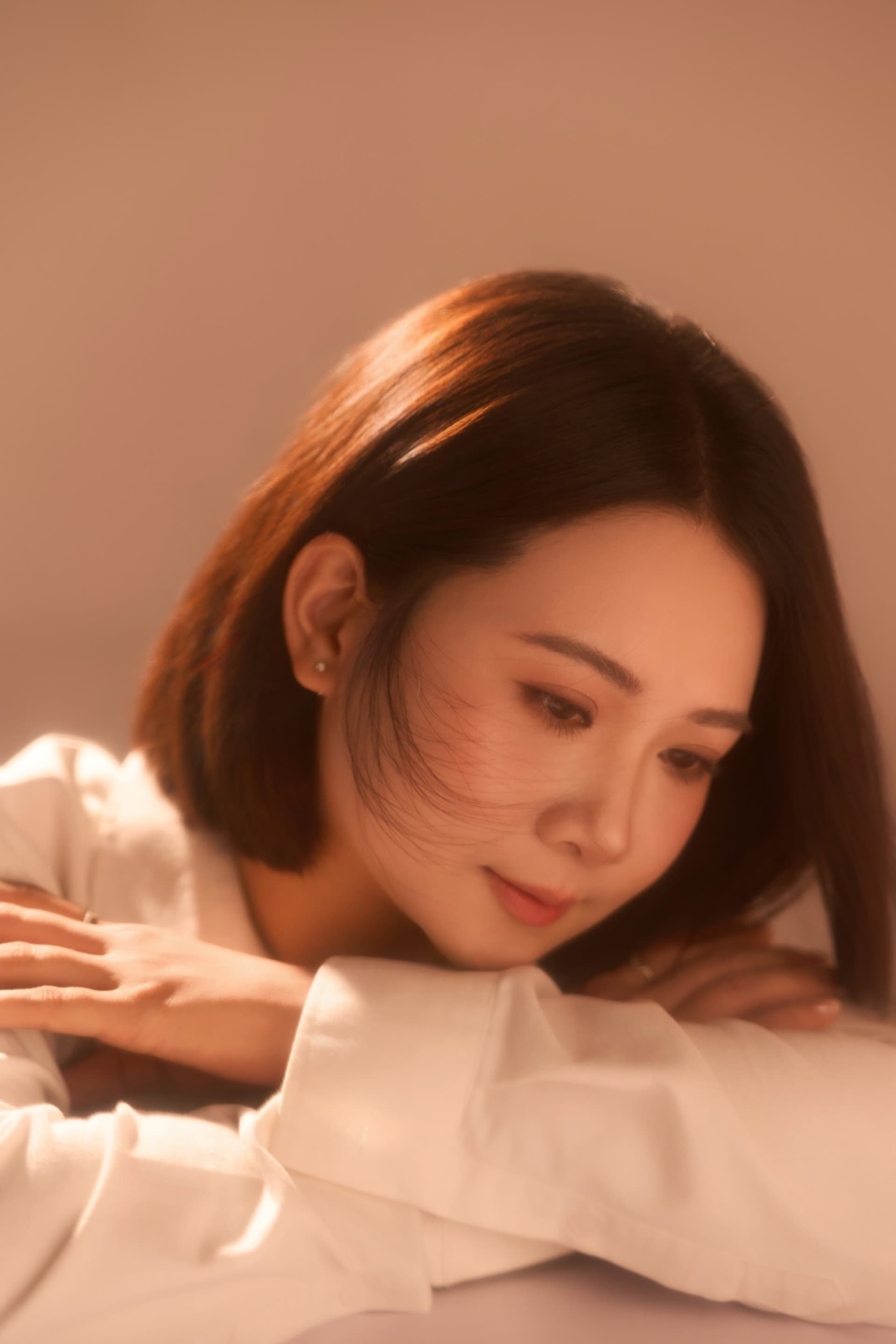 Vũ Hậu tựa cằm khẽ nghiêng đầu với nụ cười nhẹ tĩnh lặng, tựa vào bàn suy ngẫm