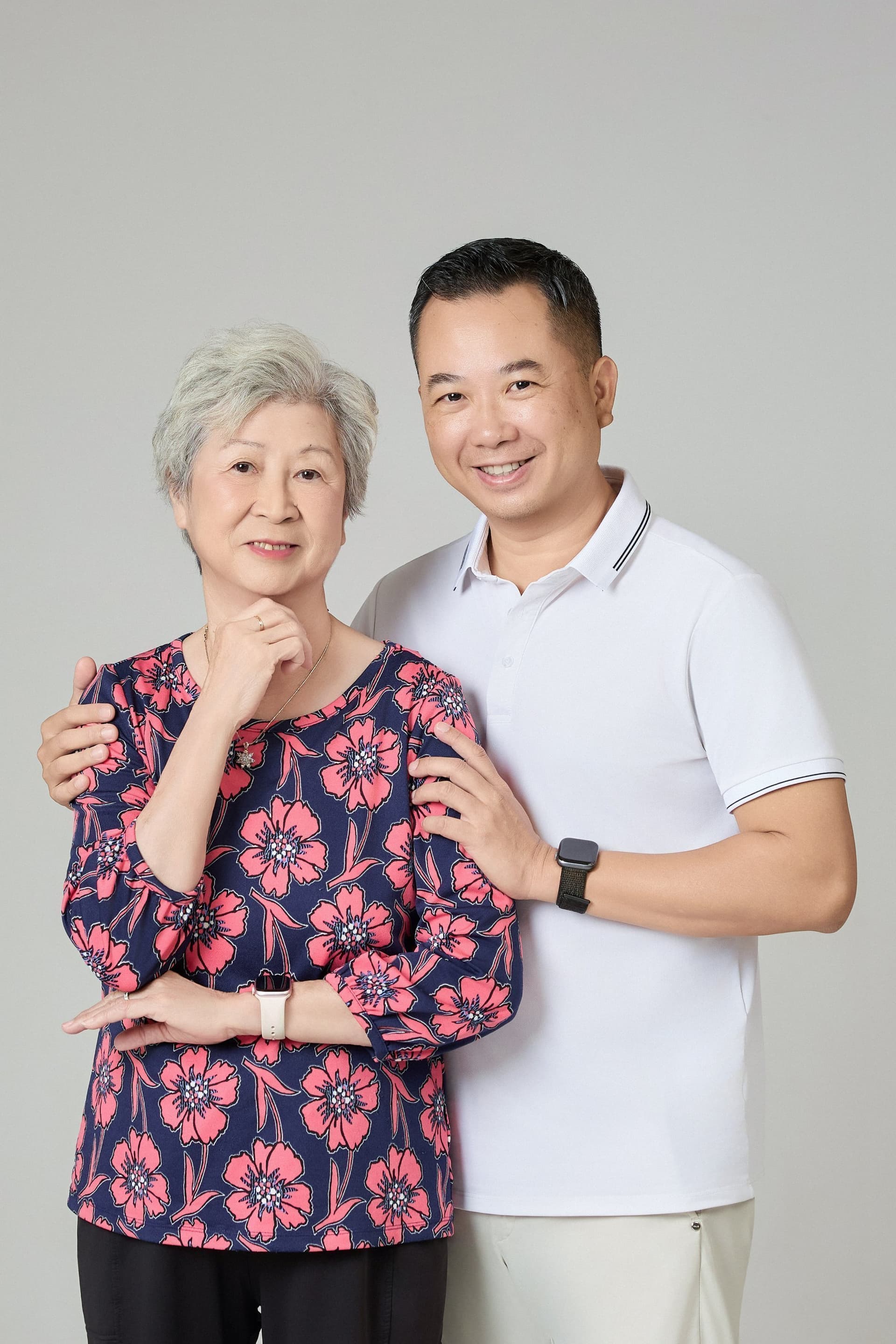 Người đàn ông áo xanh ngọc, người vợ và con trai đứng cạnh nhau, biểu cảm bình thản, nền sáng — đời thường ba người trong căn bếp Sài Gòn