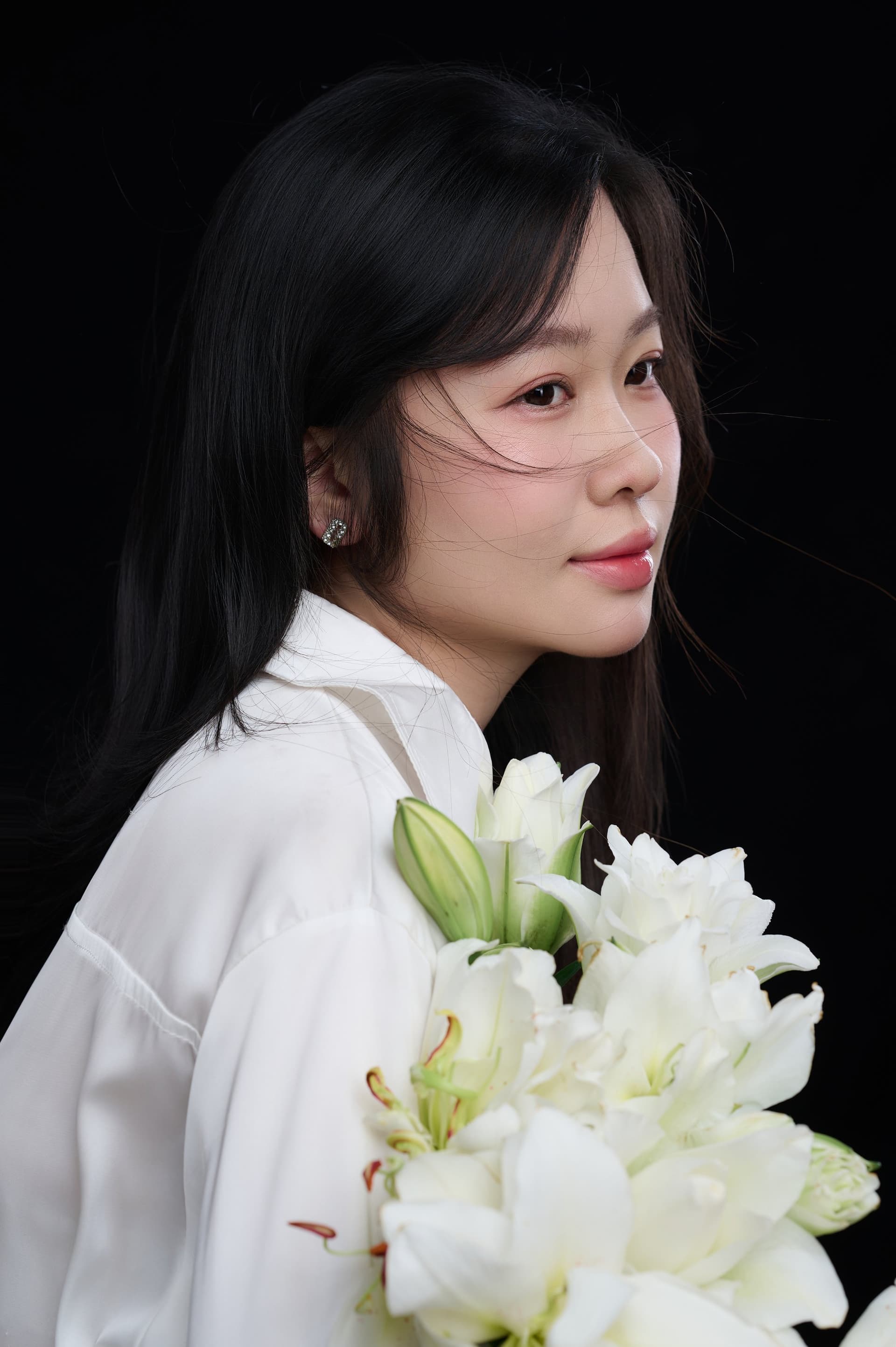 Người phụ nữ áo trắng nghiêng mặt, ánh mắt êm — vẫn giữ một nếp nhỏ thương mình giữa nhịp sống nhiều việc