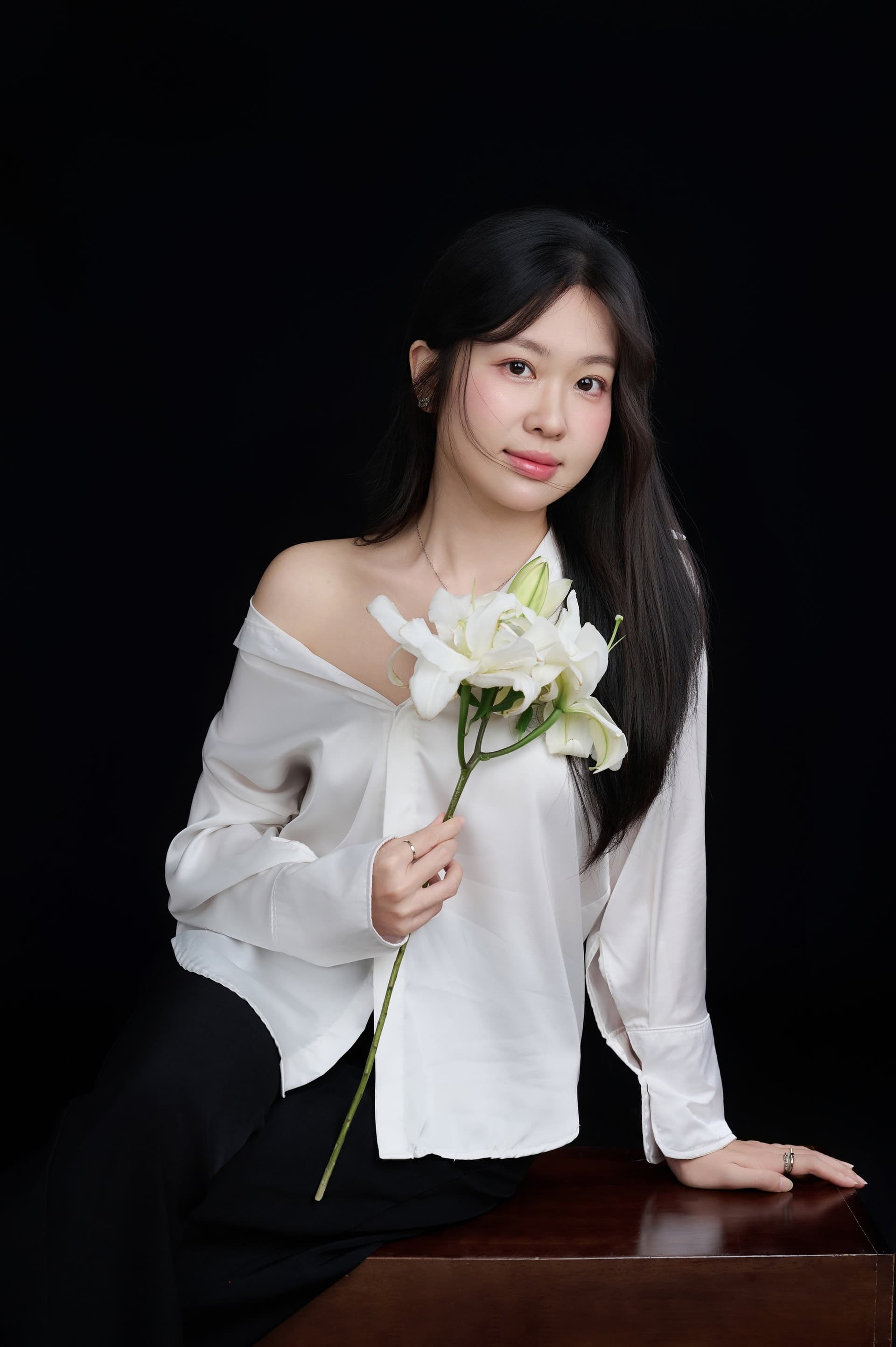 Người phụ nữ áo trắng tay ôm bó hoa loa kèn, ánh nhìn xa — một khoảng nhỏ tự nhắc mình đã đi thêm một quãng