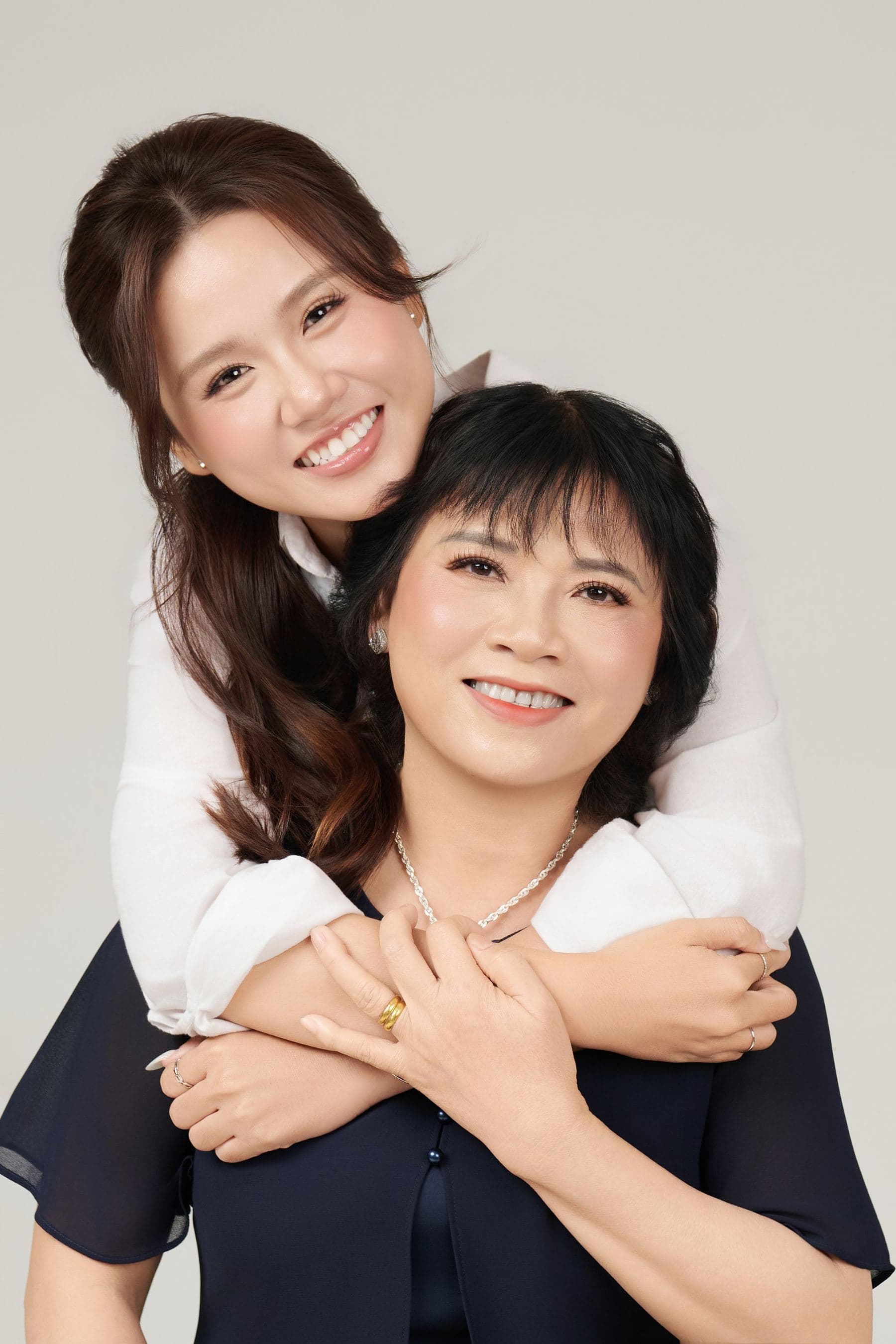 Ba và mẹ đứng cạnh nhau — sợi dây chuyền ngọc xanh, cái đồng hồ đen — hai món đồ đã đi cùng nhau từ rất lâu
