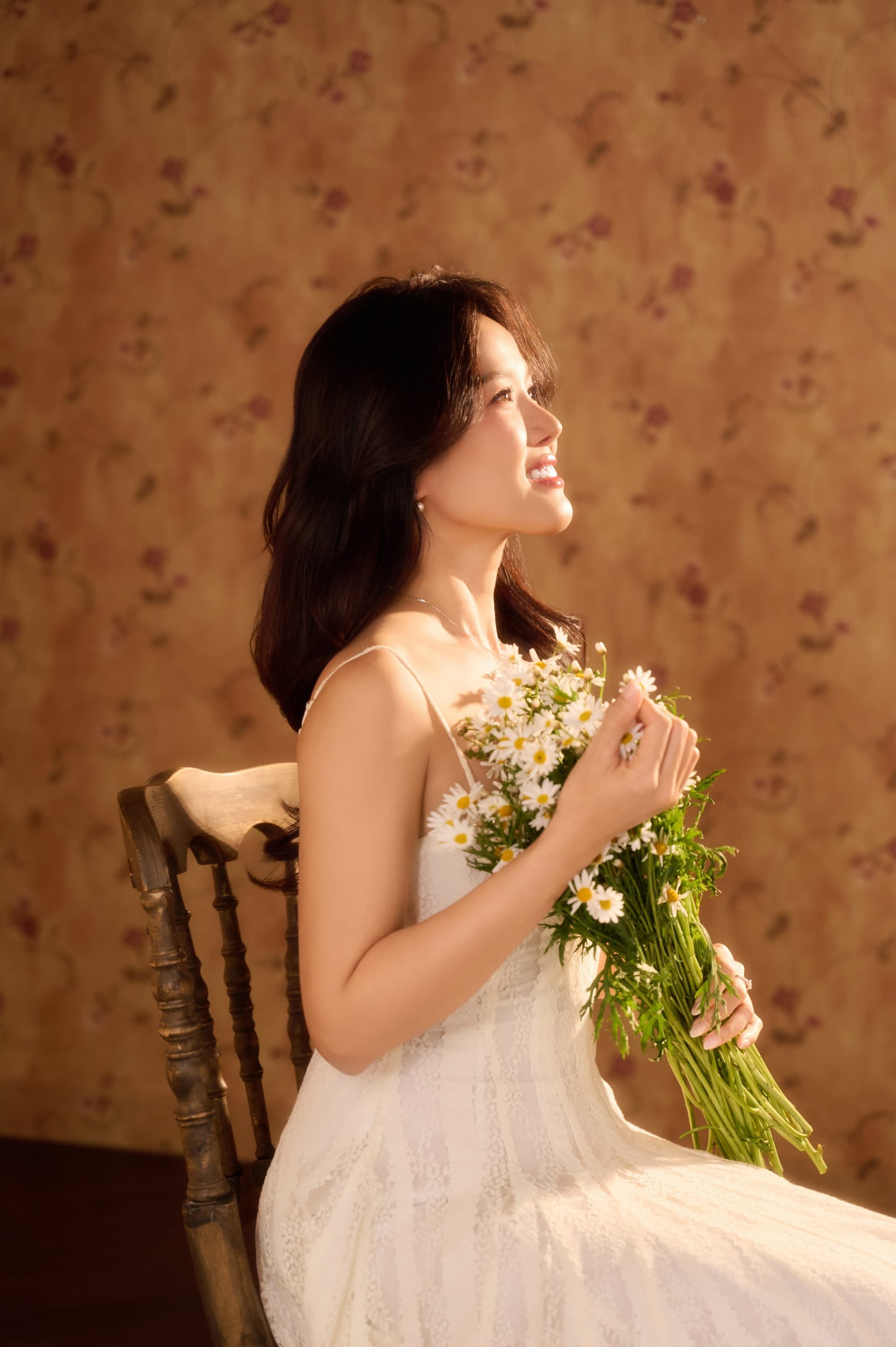 Người phụ nữ ôm bó hoa hồng trắng dại sát lồng ngực, ngước mắt nhìn lên góc nghiêng dịu dàng đầy an yên