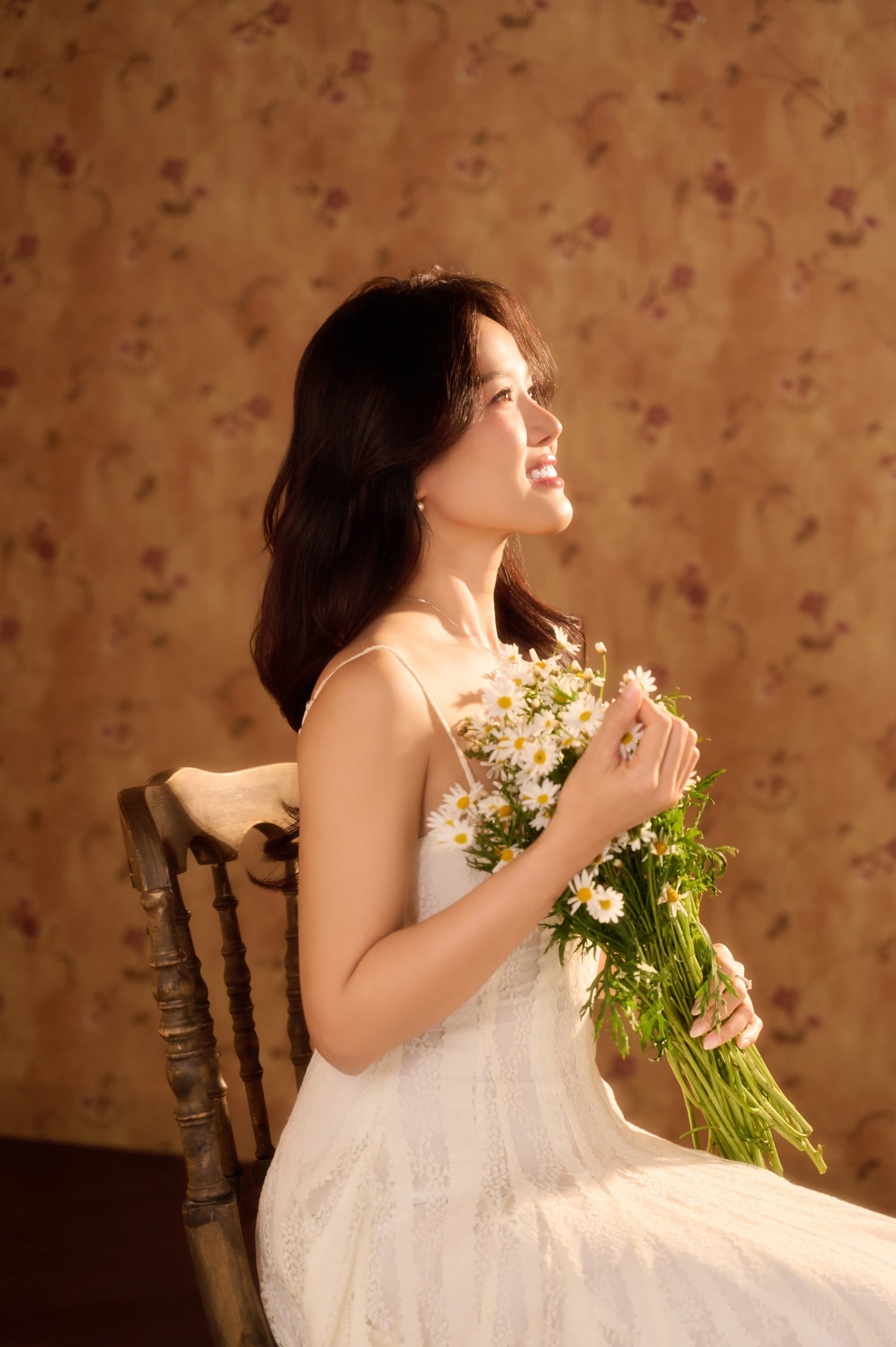 Người phụ nữ ôm bó hoa hồng trắng dại sát lồng ngực, ngước mắt nhìn lên góc nghiêng dịu dàng đầy an yên