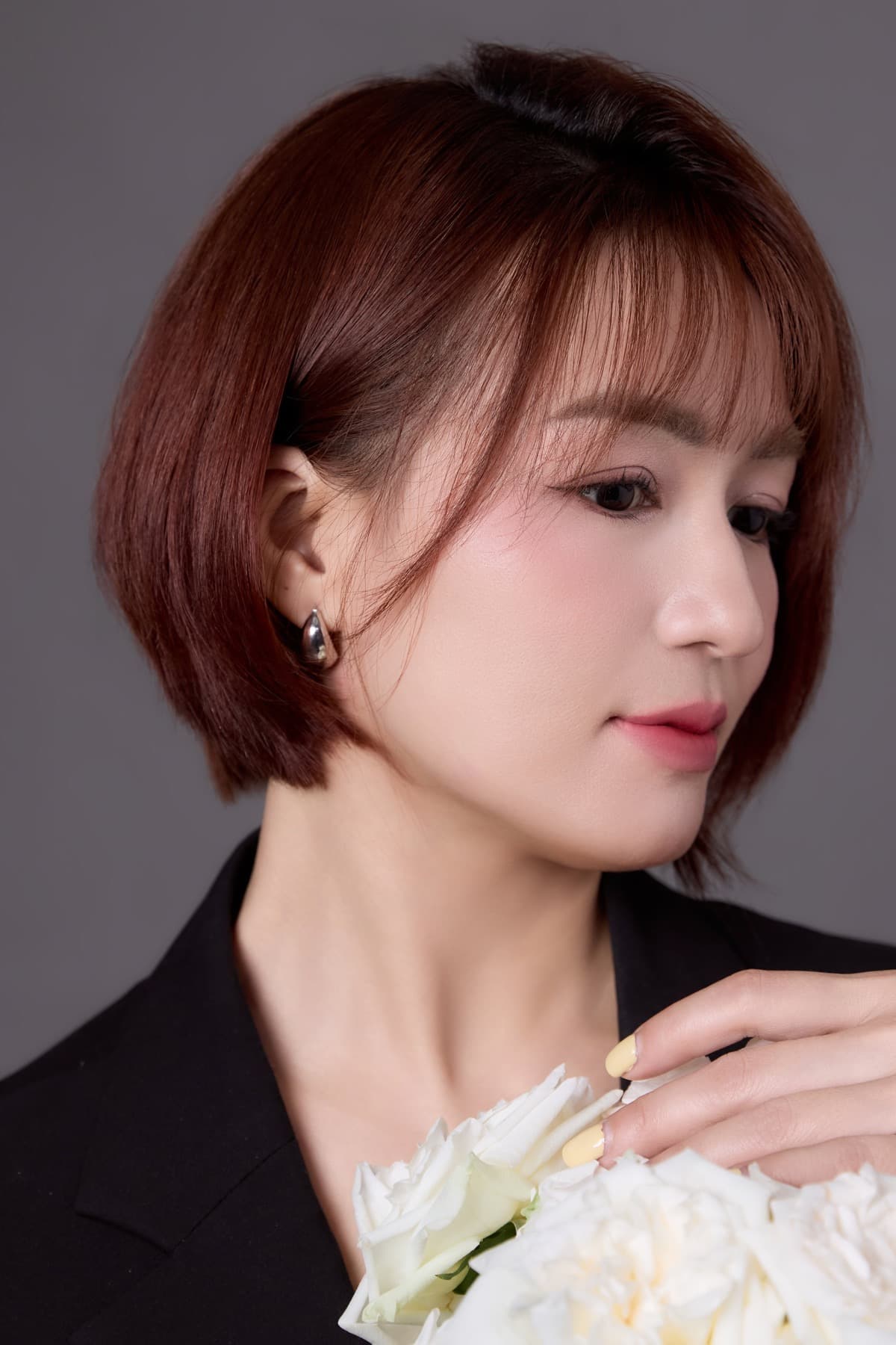 Bàn tay móng sơn vàng pastel cúi nhìn bó hoa hồng trắng — màu vàng chị tự chọn hai năm trước vẫn còn nguyên đợi