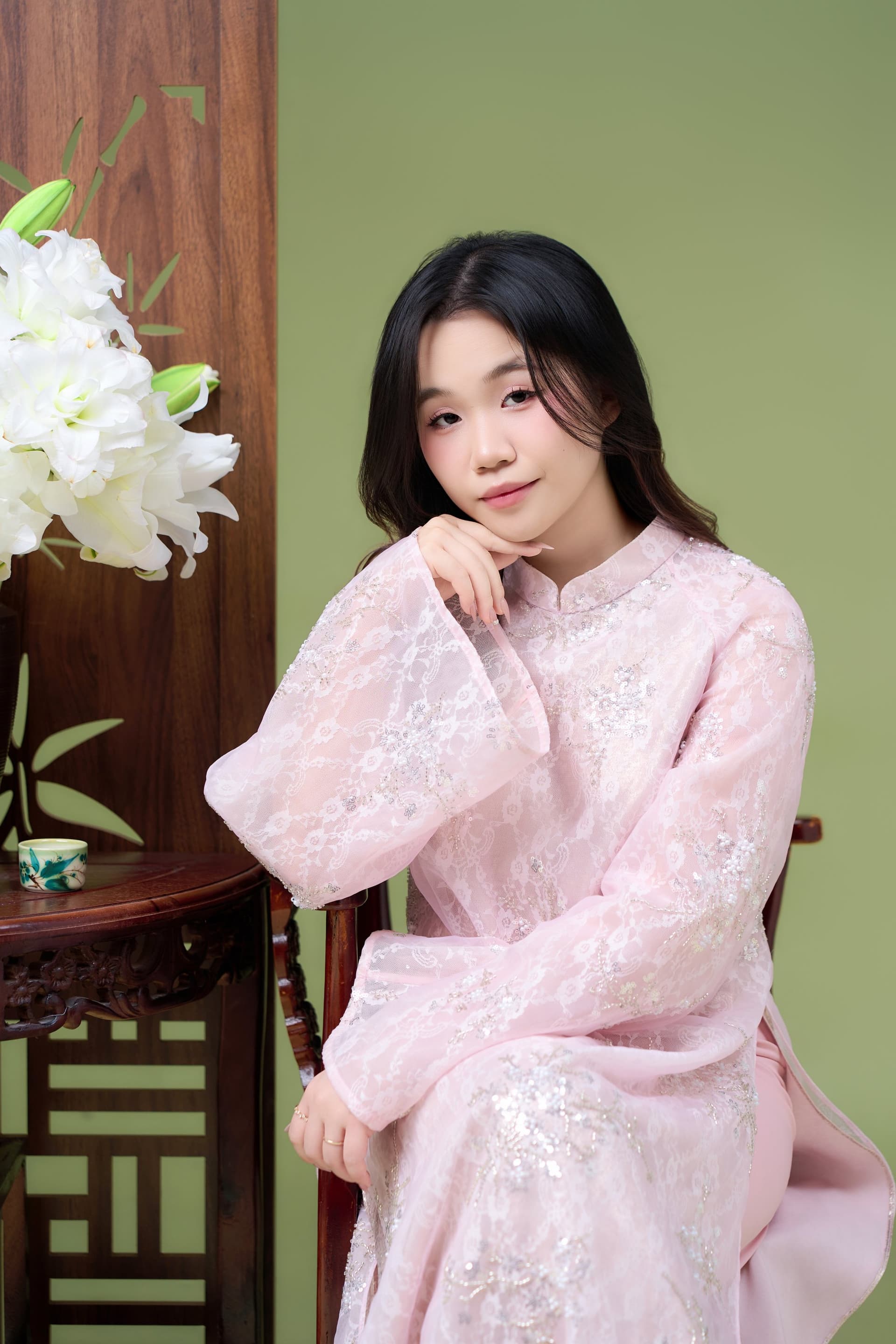 Người vợ xinh đẹp trong bộ áo dài màu hồng, nở nụ cười mỉm e ấp tự nhiên