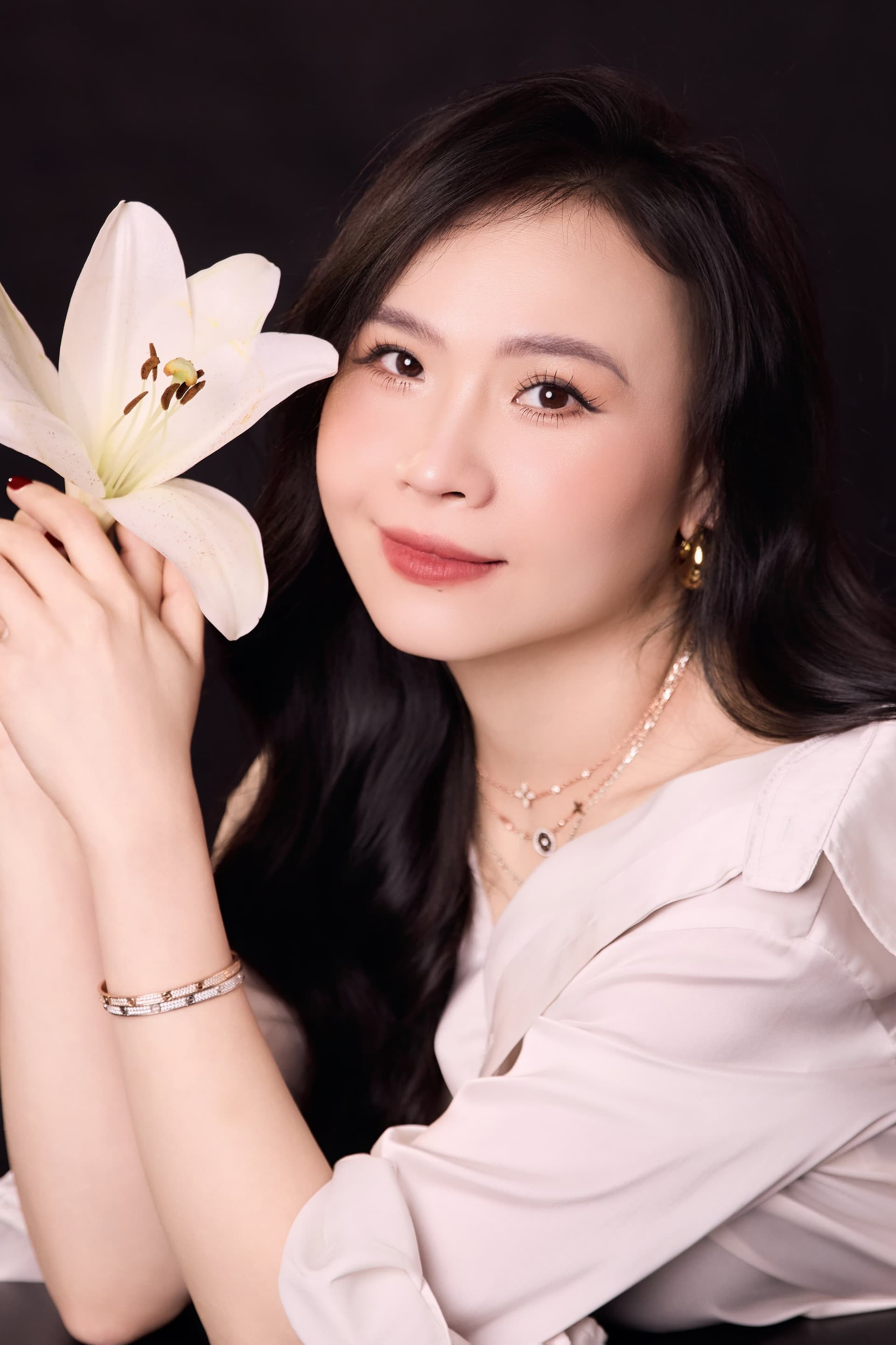 Chân dung chị Lý Lưu cầm bông hoa huệ trắng gần gương mặt và mỉm cười nhẹ nhàng thanh thoát