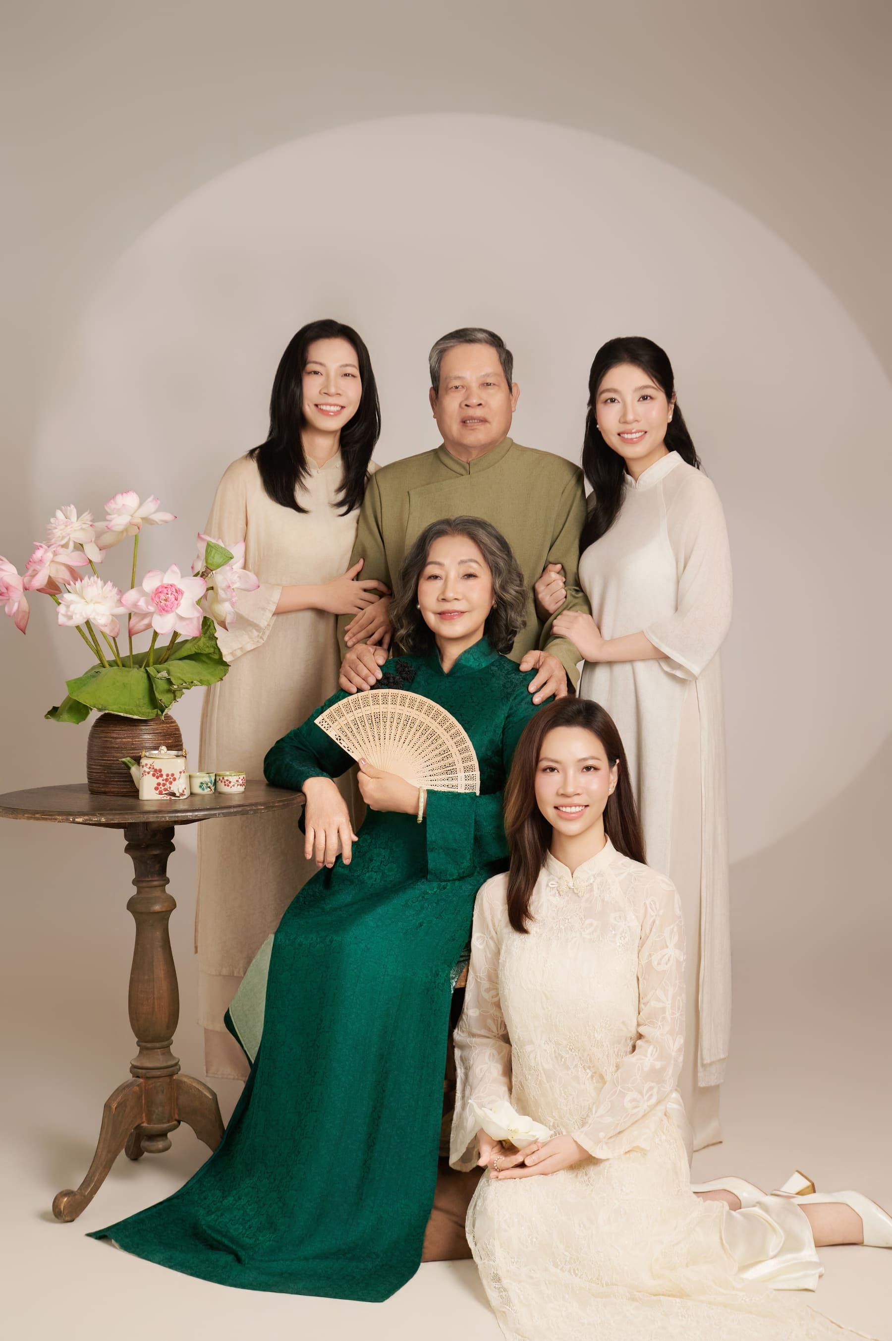 Gia đình năm người đủ mặt trong áo dài xanh trắng, người mẹ ngồi giữa ba con và người bạn đời
