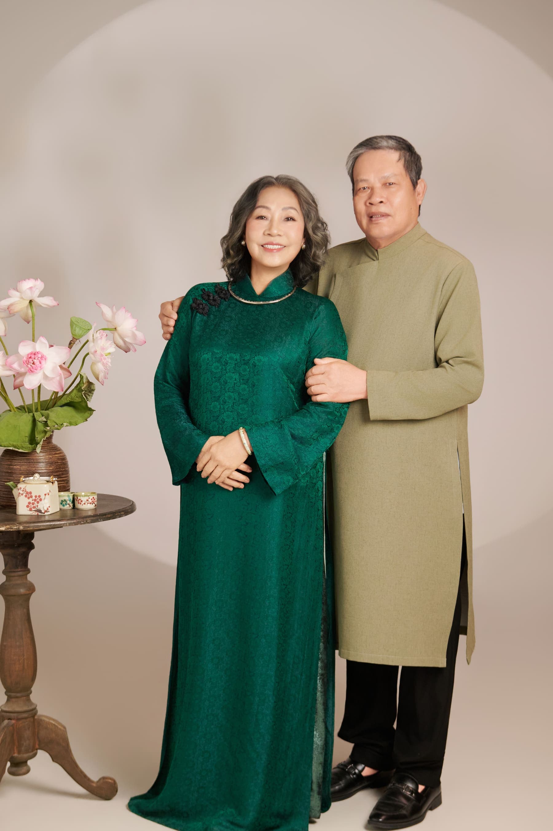 Hai vợ chồng đứng cạnh nhau trong áo dài xanh, dáng bình yên của một mái nhà nhiều năm