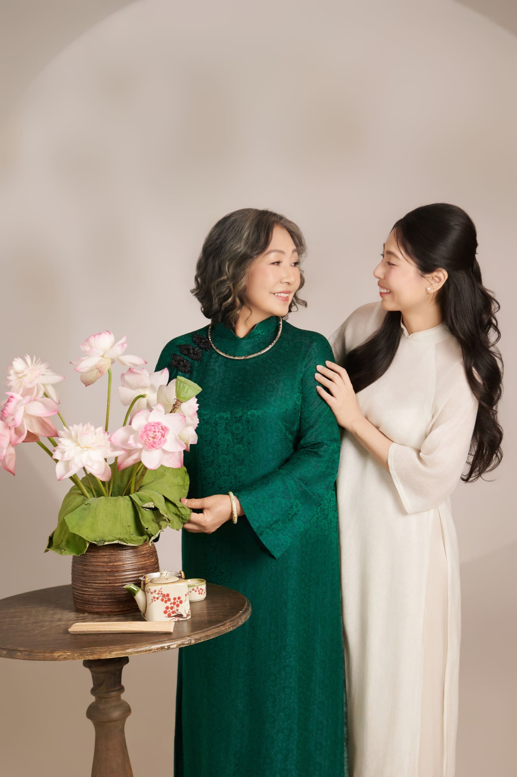 Người mẹ áo xanh nhìn con gái trong tà áo trắng, ánh mắt dịu của hai thế hệ trong nhà