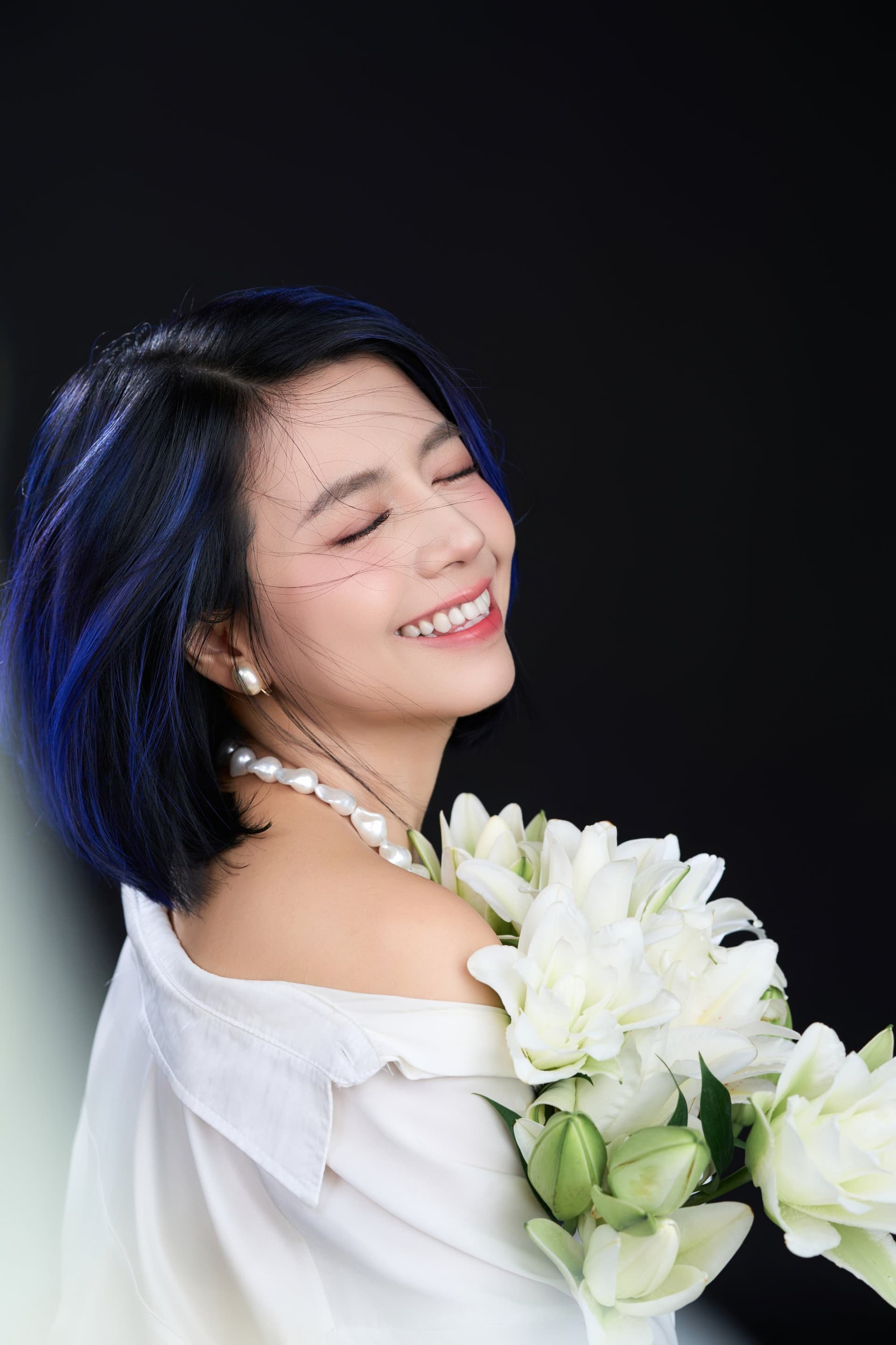 Cô gái kề má vào bó hoa lily, mắt khép nhẹ — khoảnh khắc thoải mái với chính mình