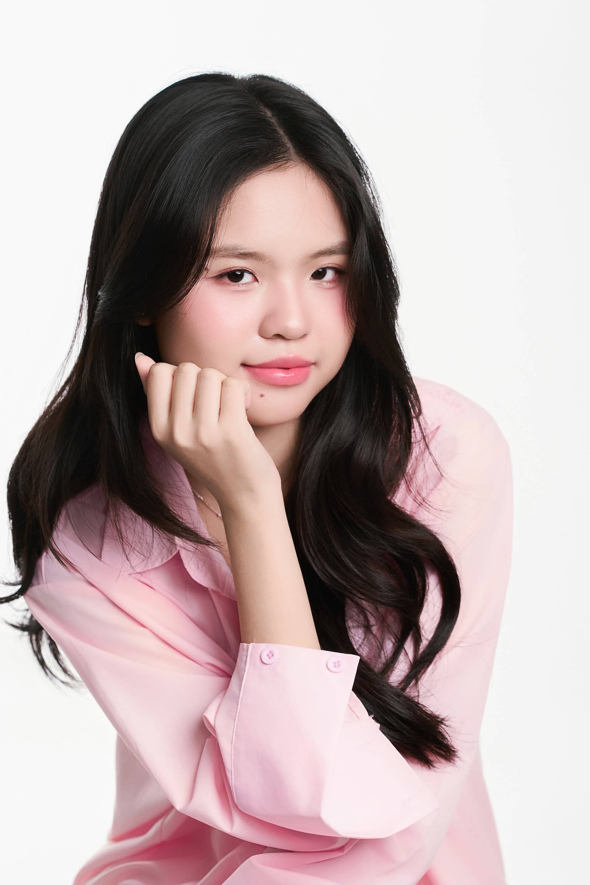 Cô gái trẻ chống tay lên má nhìn thẳng vào ống kính với đôi mắt trong veo và nét mặt dịu nhẹ