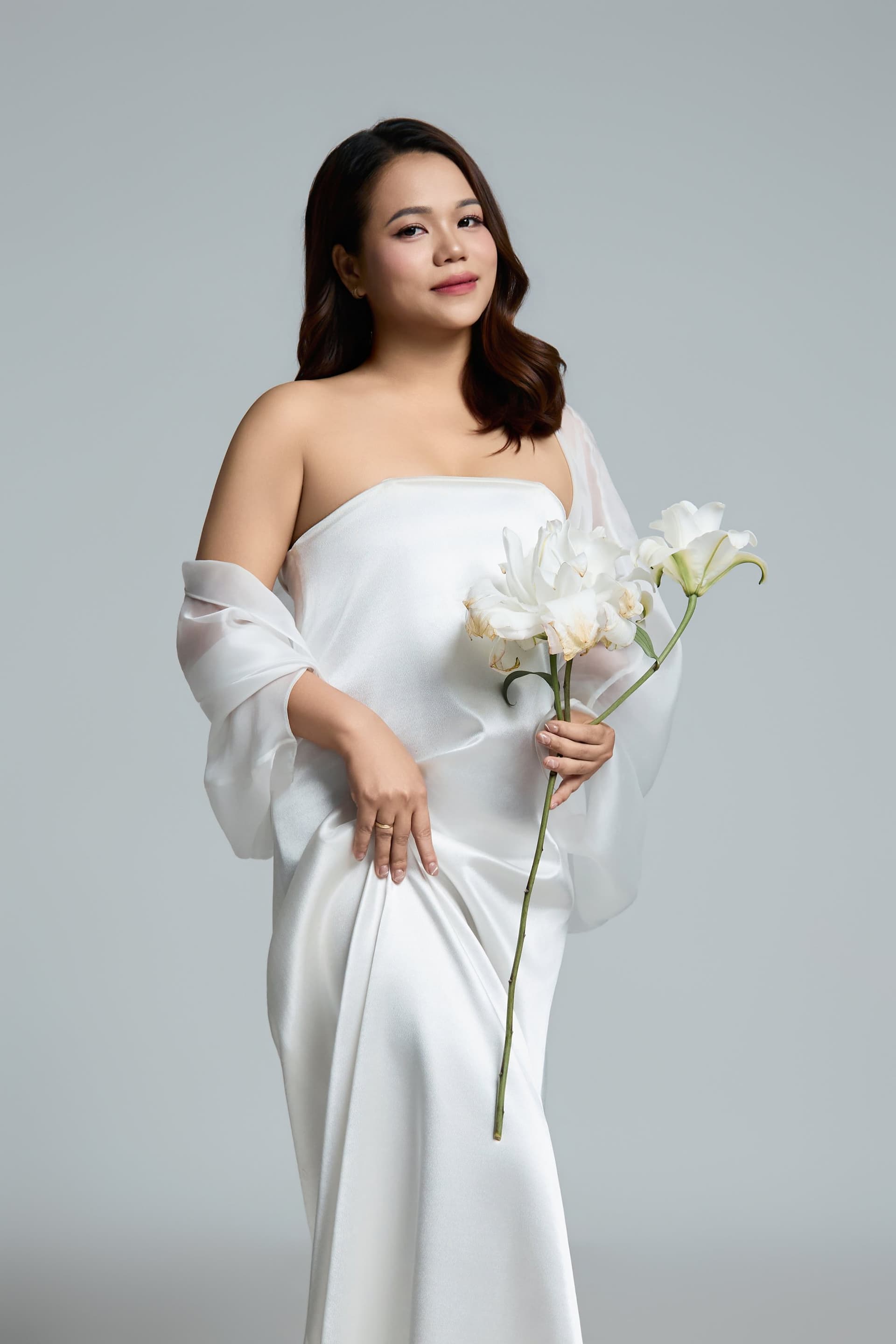 Chân dung người cháu nội trở về ôm bó hoa cẩm chướng trắng, mang vẻ đẹp dịu dàng và suy tư trong không gian studio ấm cúng