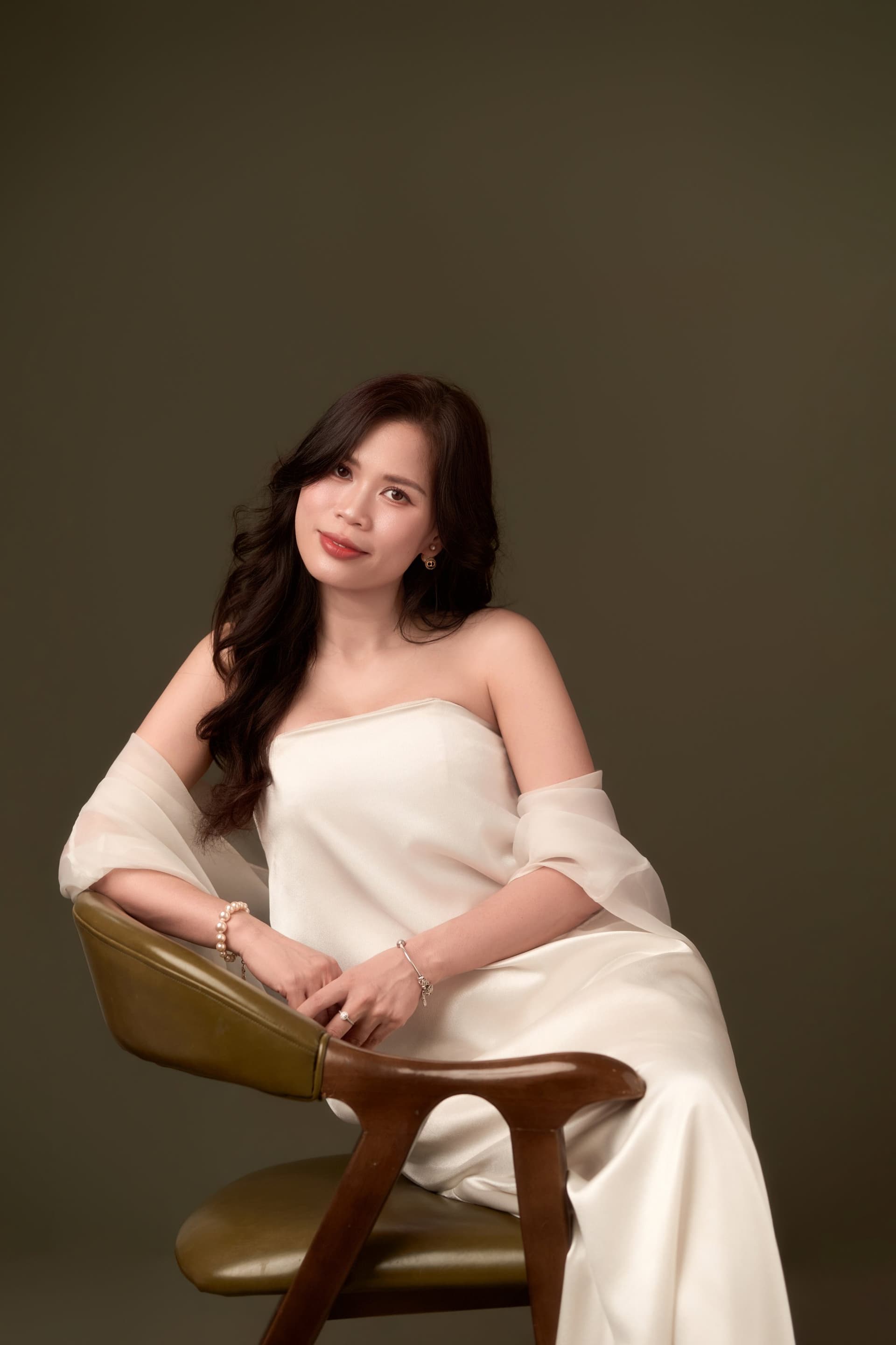 Người phụ nữ áo trắng nghiêng đầu nhẹ, mắt khép xuống, đường nét gương mặt dịu lại — phần mềm cất ở đáy tủ, có một mùa được mở ra