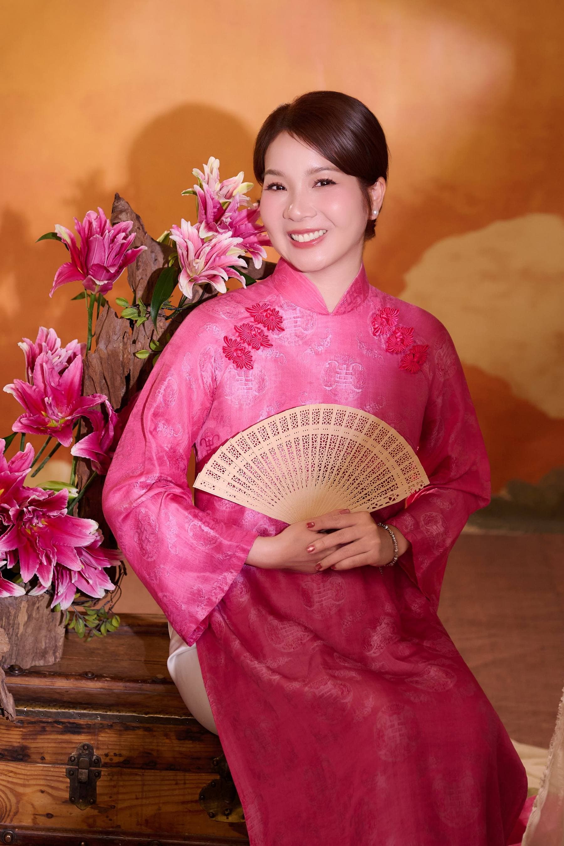 Chị Thanh trong tà áo dài hồng, cận mặt — tà áo cũ mẹ vẫn treo trong tủ