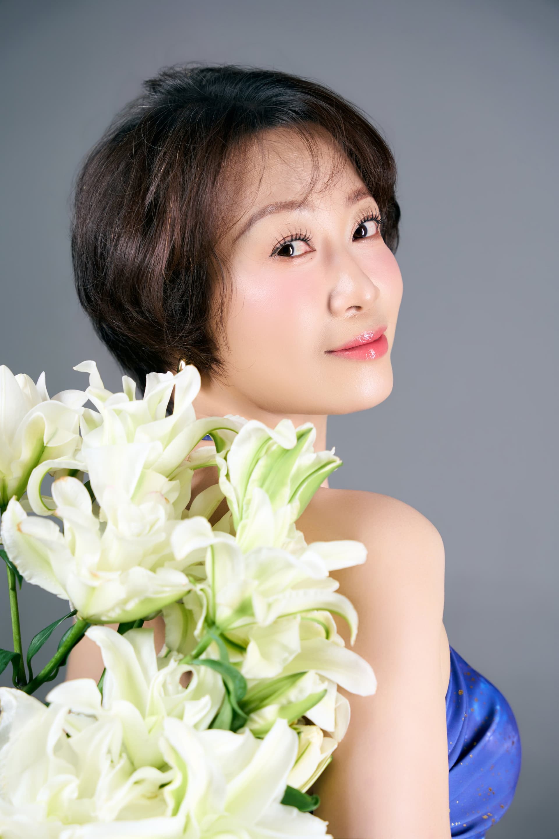 Người phụ nữ áo đen ôm bó hoa lily trắng cuống dài — khoảnh khắc đầu tiên dành cho riêng mình sau nửa đời đứng giữa người khác