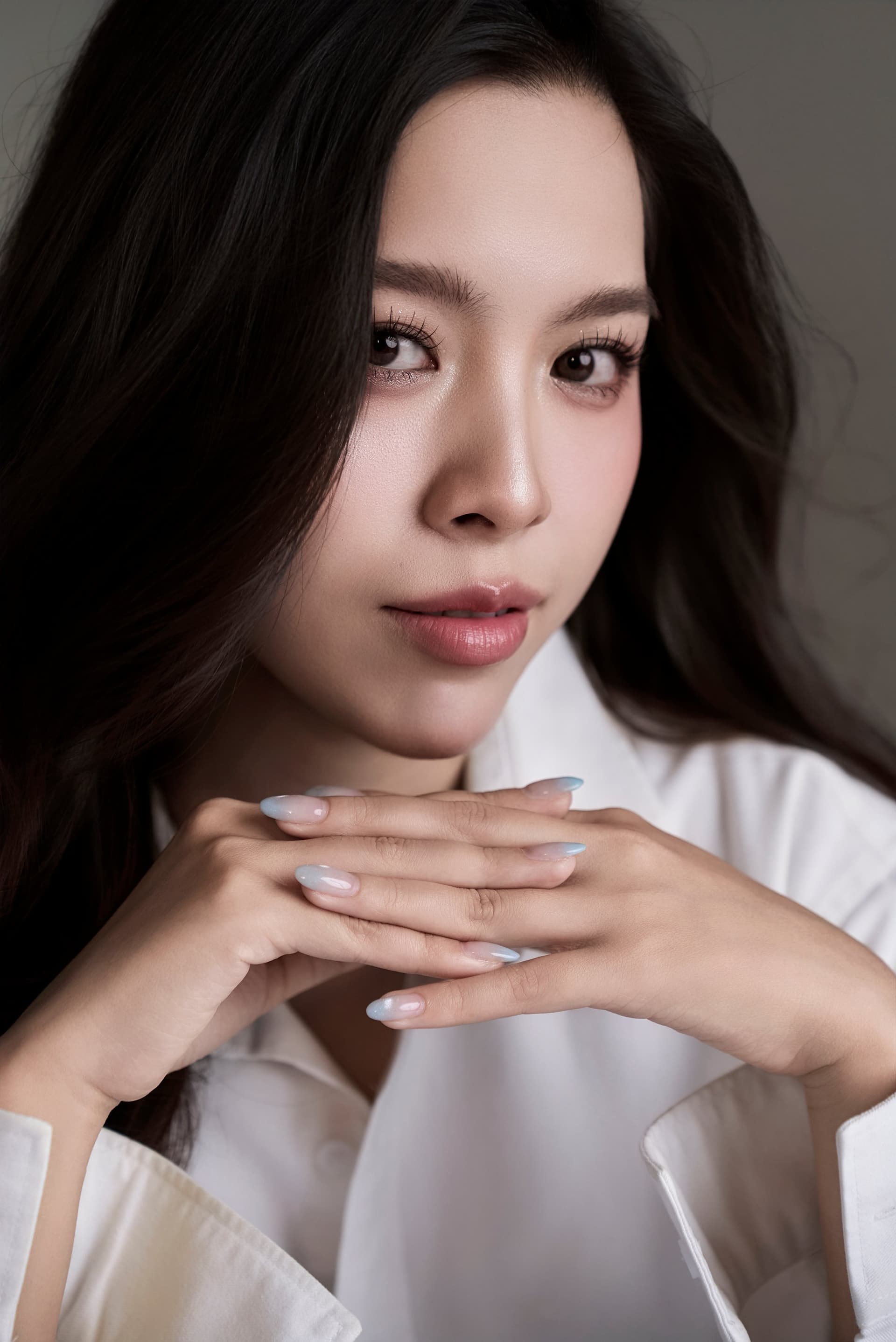 Cô gái áo sơ mi trắng tựa cằm, ánh mắt xa, gương mặt dịu — cô gái sinh đầu những năm 2 nghìn dừng lại với chính mình