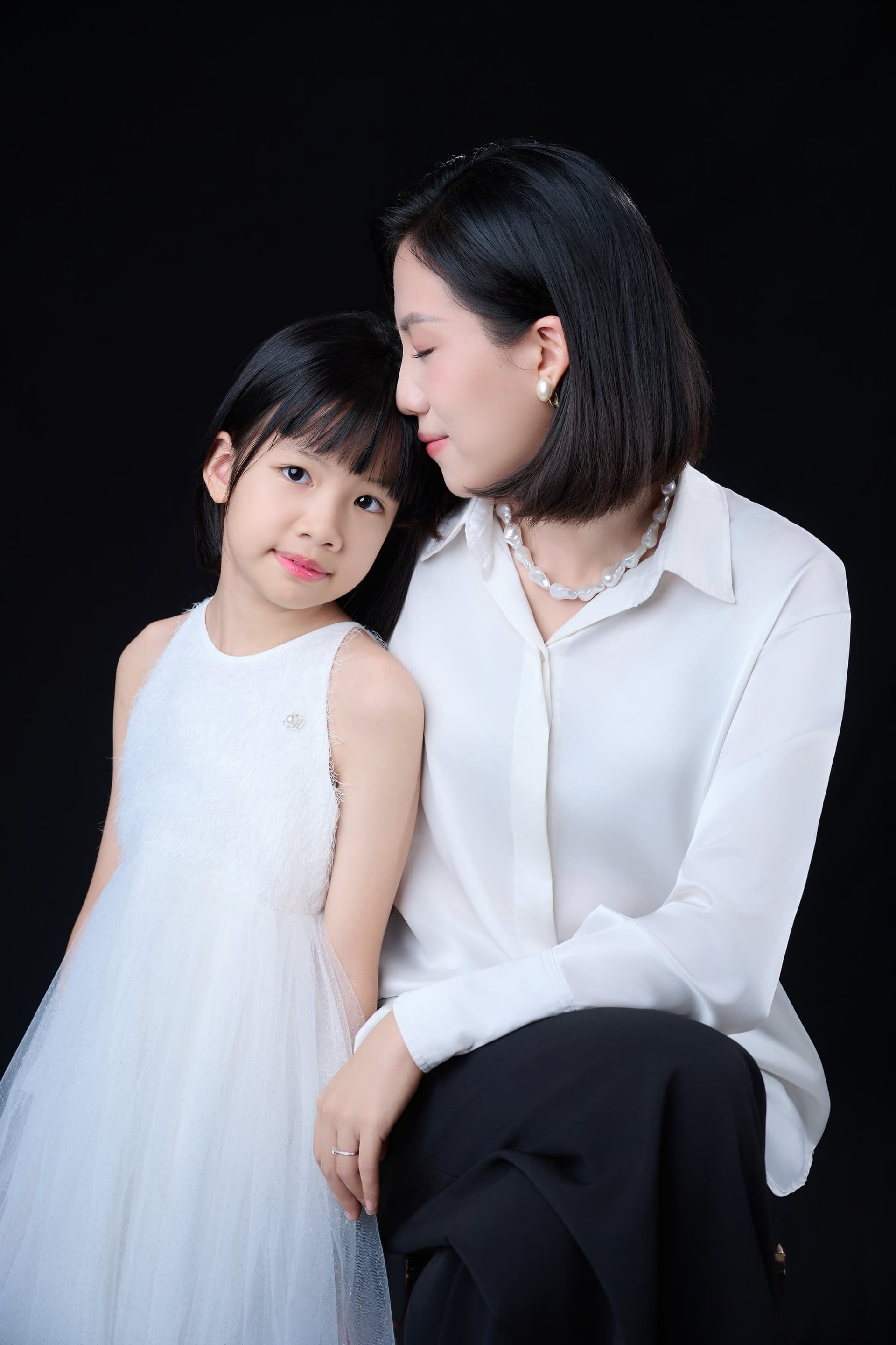 Người mẹ ôm bó hoa trắng, con gái nhỏ tựa vào vai — nhịp ngày của một người đã quen đặt cả nhà lên trước