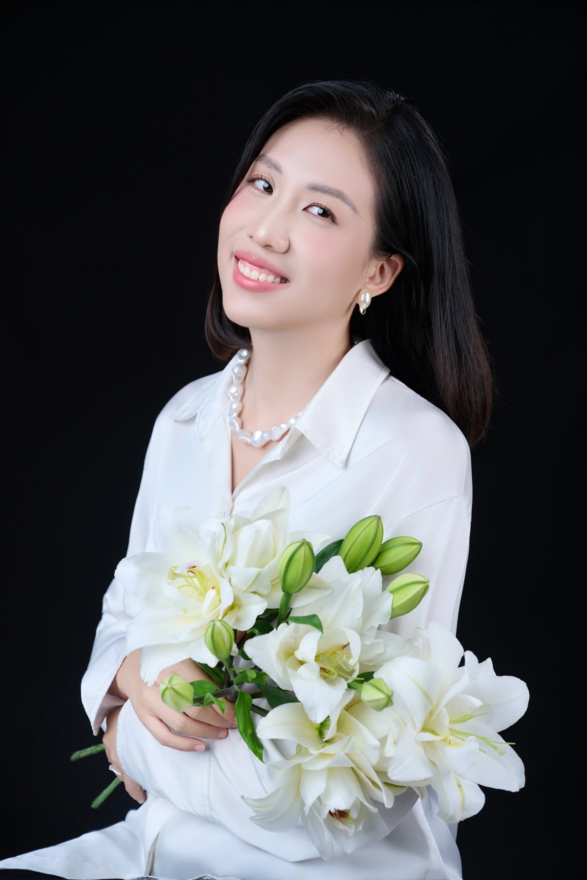 Người phụ nữ ôm bó hoa lily trắng, gương mặt nghiêng dịu, ánh sáng êm — lần trở về dành cho mình một phần riêng