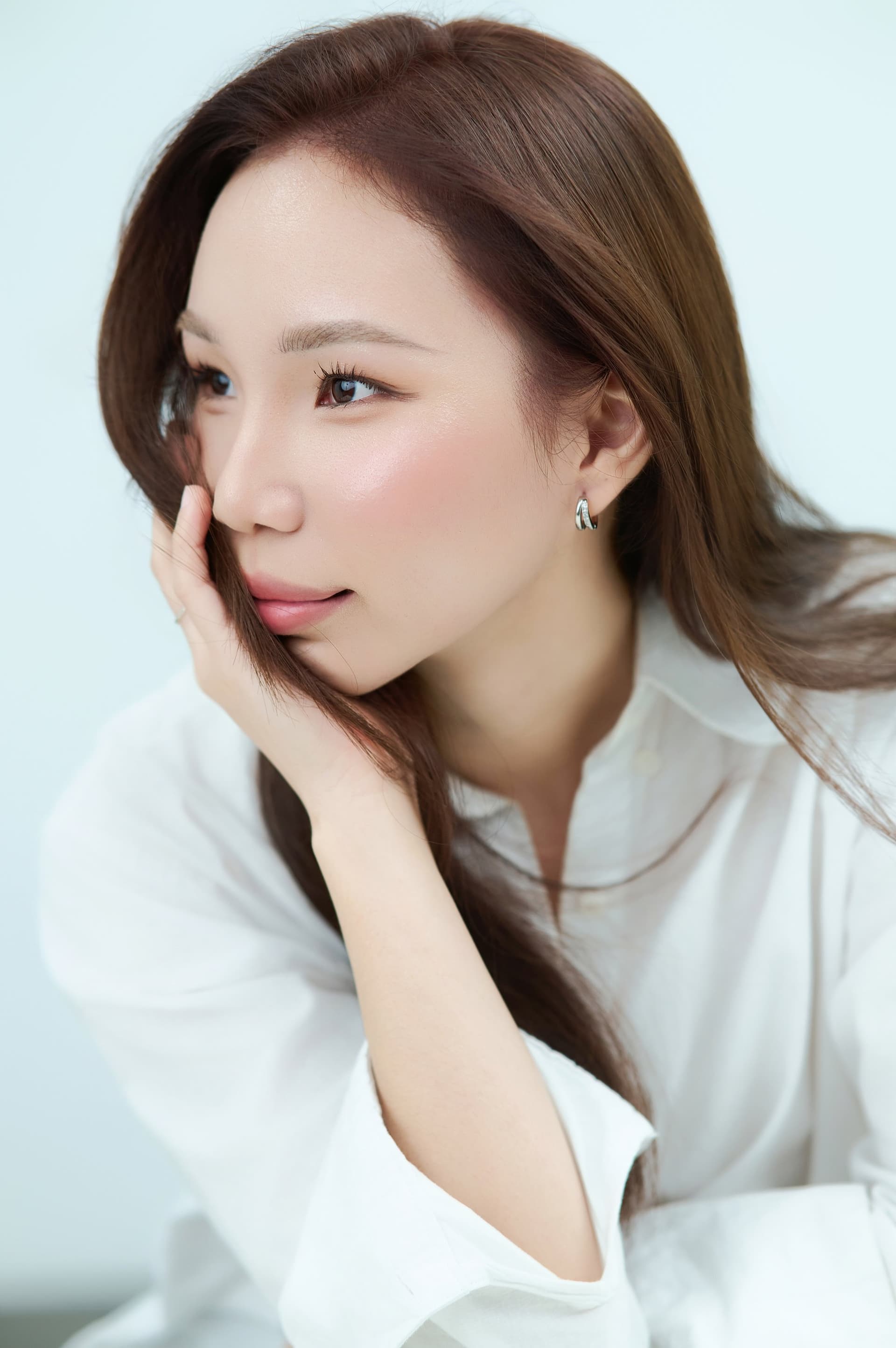 Người phụ nữ tay đặt má, ánh mắt nhìn xa, makeup mềm — chân dung bán thân ngang