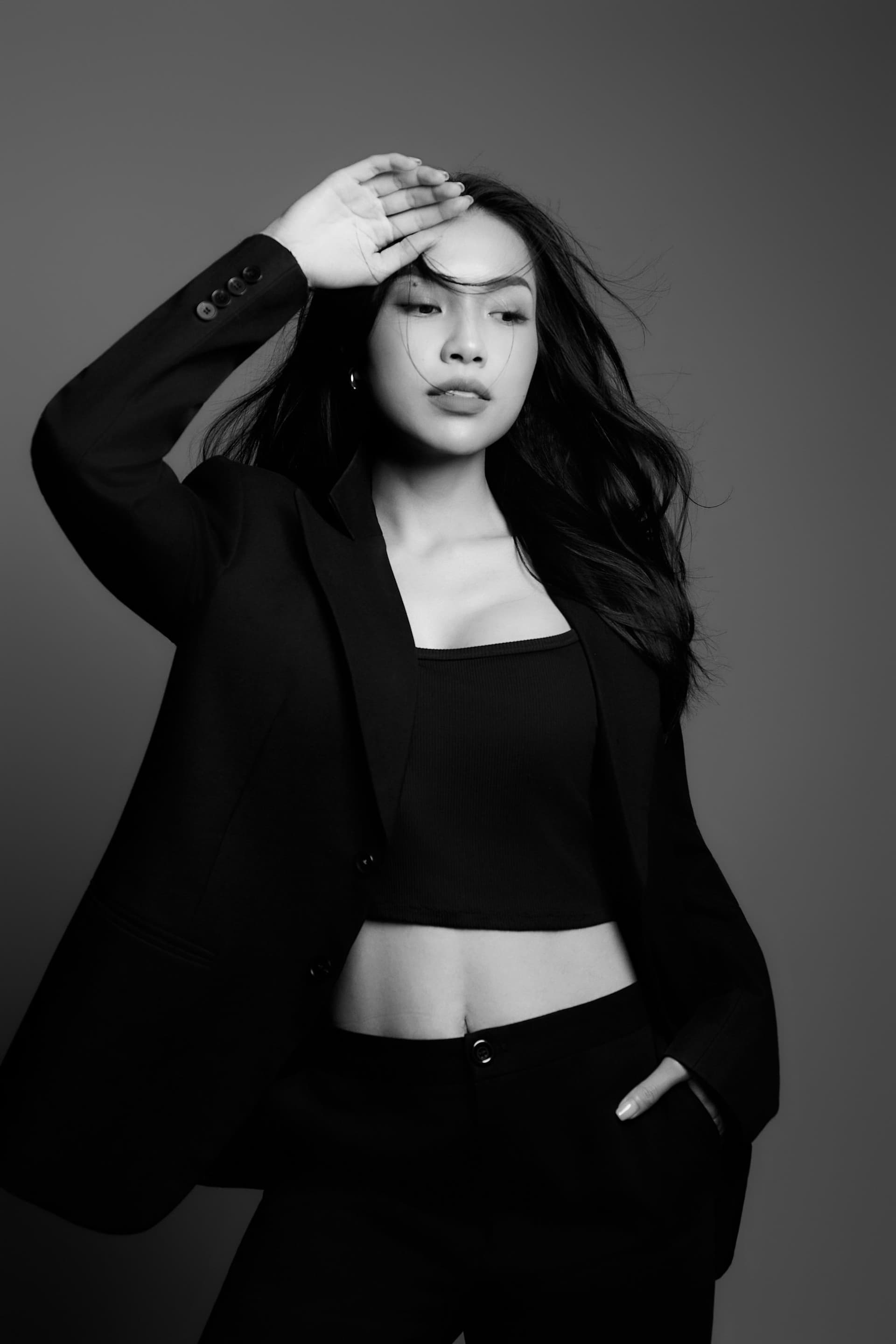 Julie đứng nghiêng mình nhẹ nhàng khoác hờ chiếc áo blazer đen cổ điển đầy cá tính