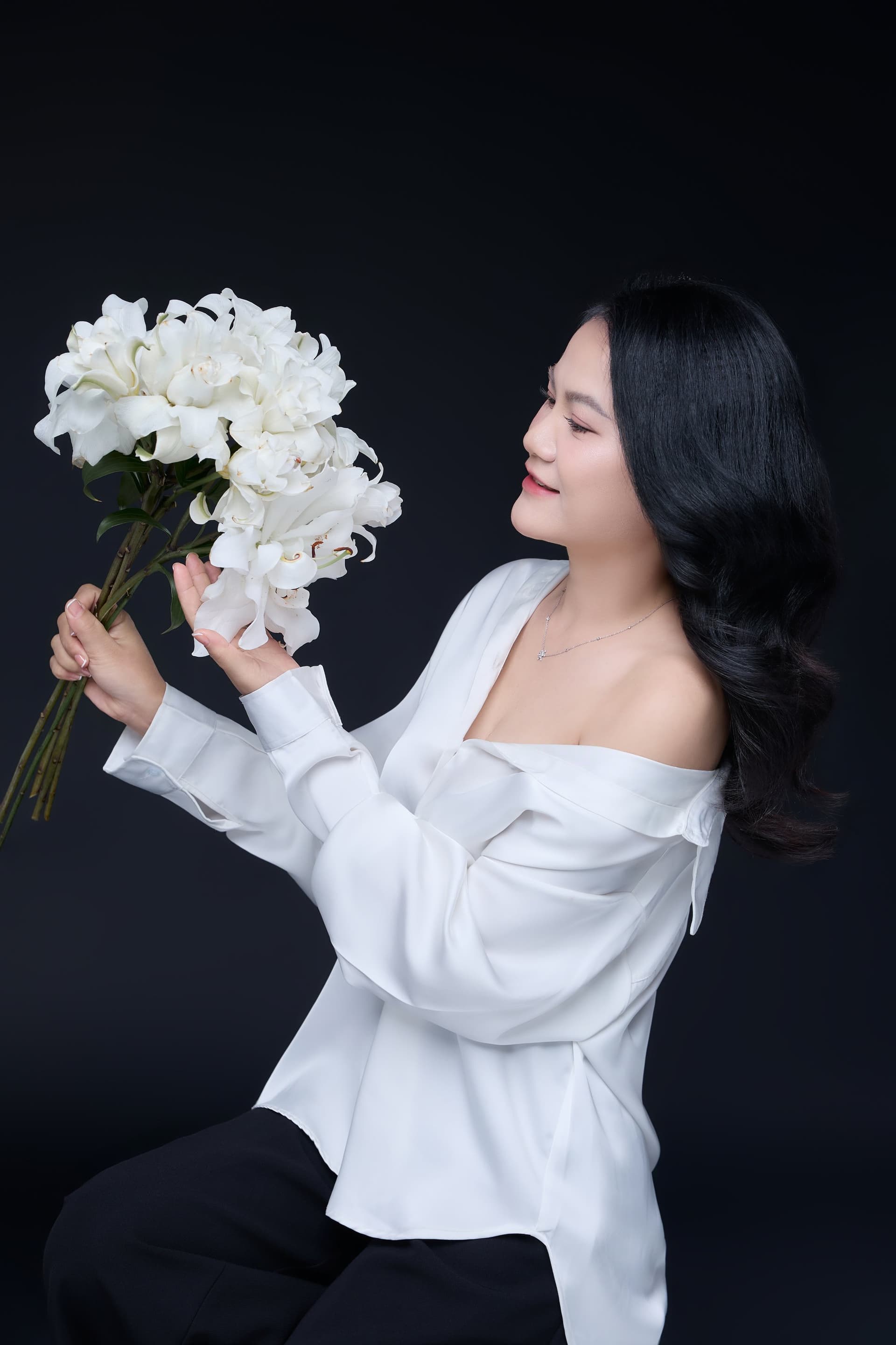 Đôi tay dịu dàng của Hà Nguyễn nâng đóa hoa trắng thanh khiết, ánh mắt nhìn xuống nhẹ nhõm