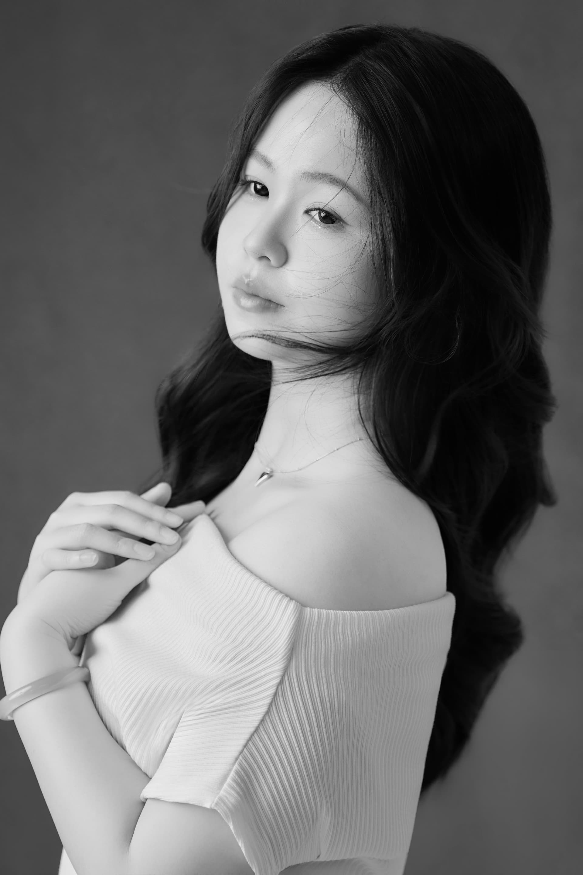 Linh trong chiếc váy trắng trễ vai dịu dàng dưới ánh sáng ấm áp của phòng studio