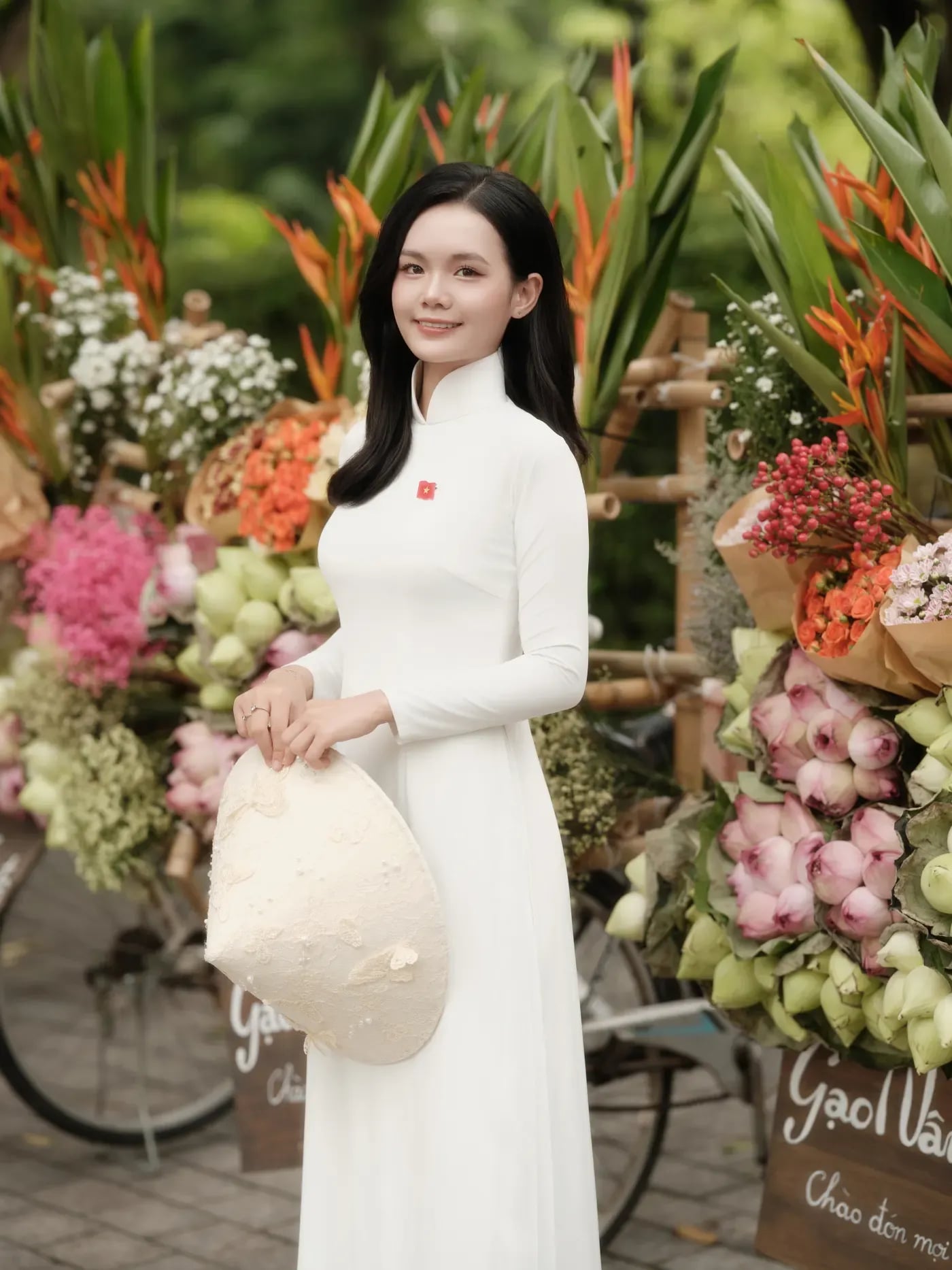 Nữ sinh áo dài trắng bên hoa trong không gian xanh Hà Nội