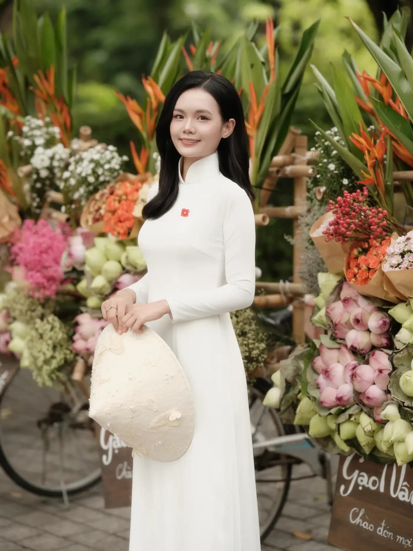Nữ sinh áo dài trắng bên hoa trong không gian xanh Hà Nội