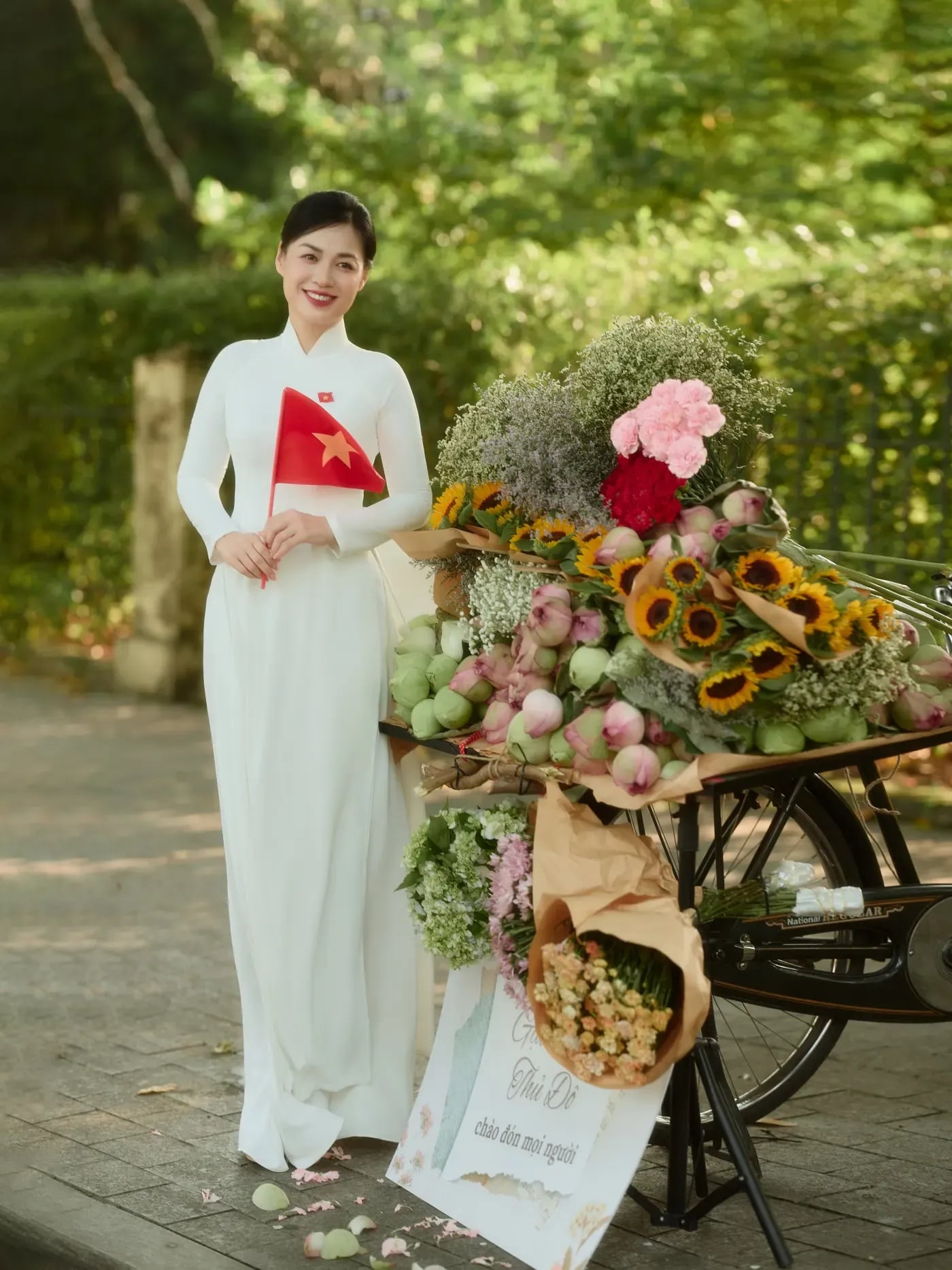 Áo dài trắng cầm cờ nhỏ trong không gian cây xanh Hà Nội