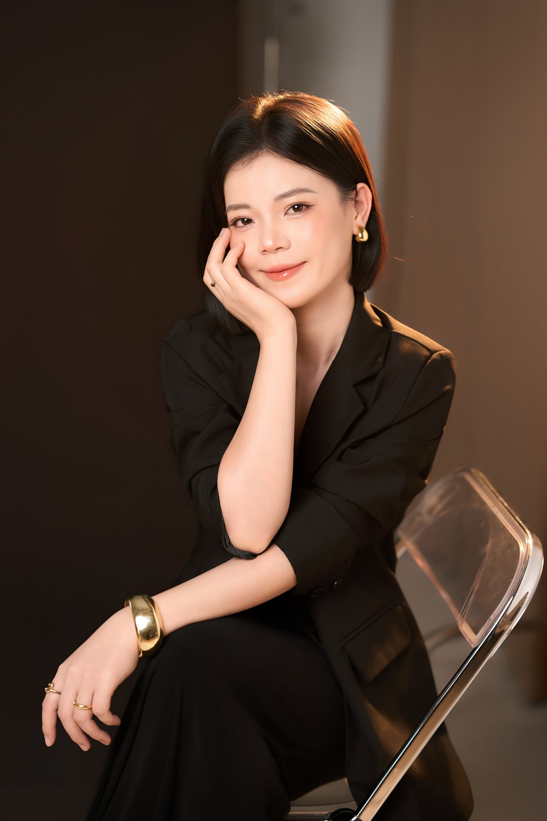 Phương Phạm tựa lưng nhẹ nhõm trên chiếc ghế trong phòng chụp, mỉm cười tự nhiên thể hiện sự tự tin ấm áp