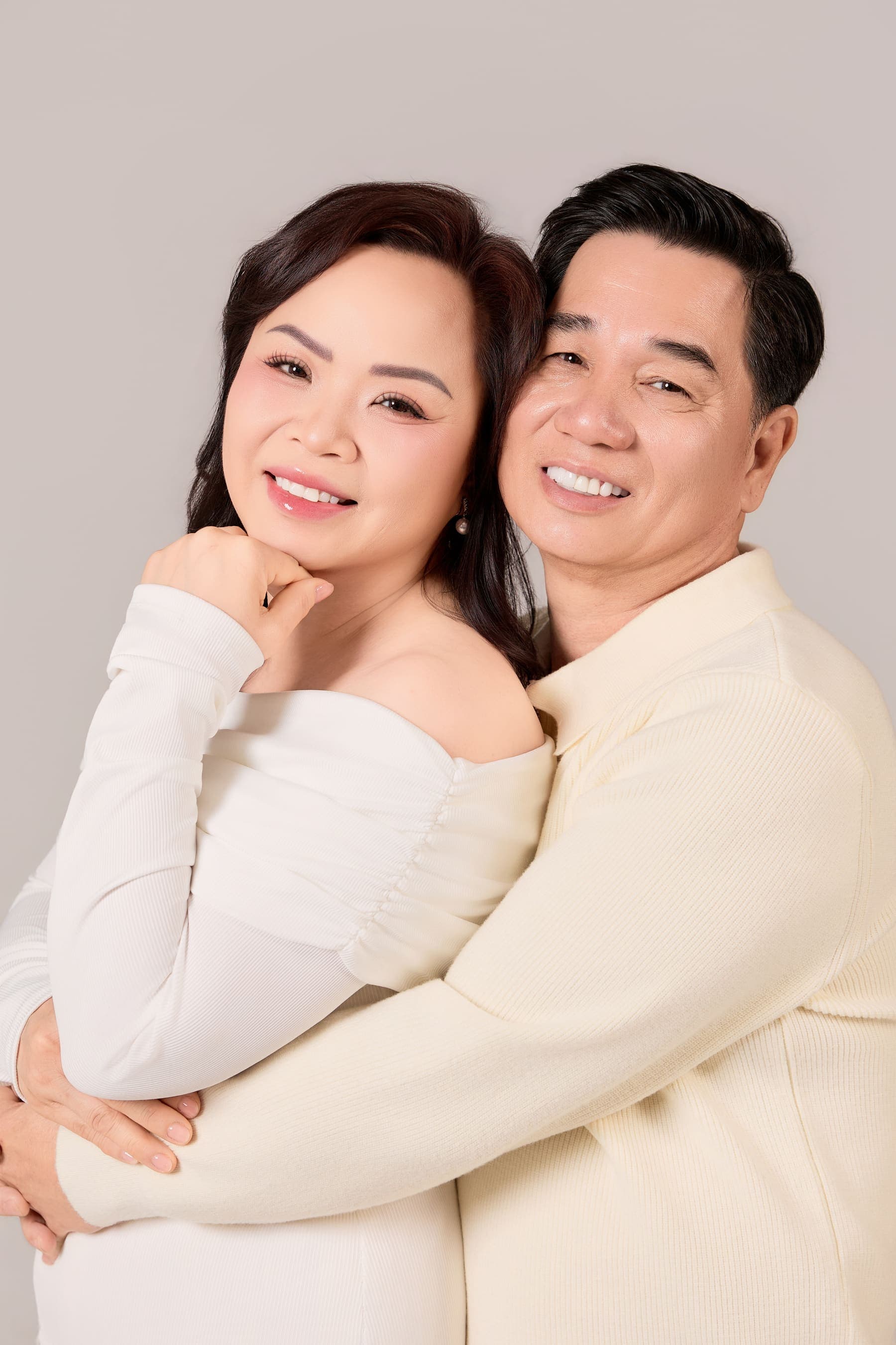 Hai vợ chồng tựa vào nhau cười gần khung hình, gương mặt sáng và thân mật