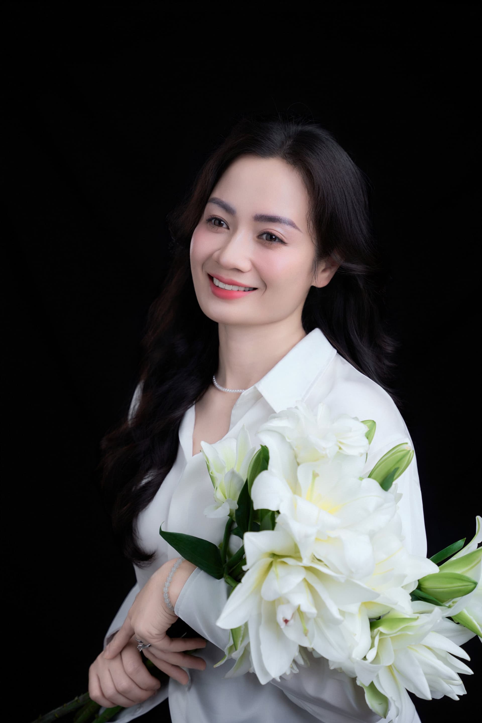 Chị Phương Thủy mỉm cười nhẹ nhàng và rạng rỡ khi ôm bó hoa loa kèn trắng thanh lịch