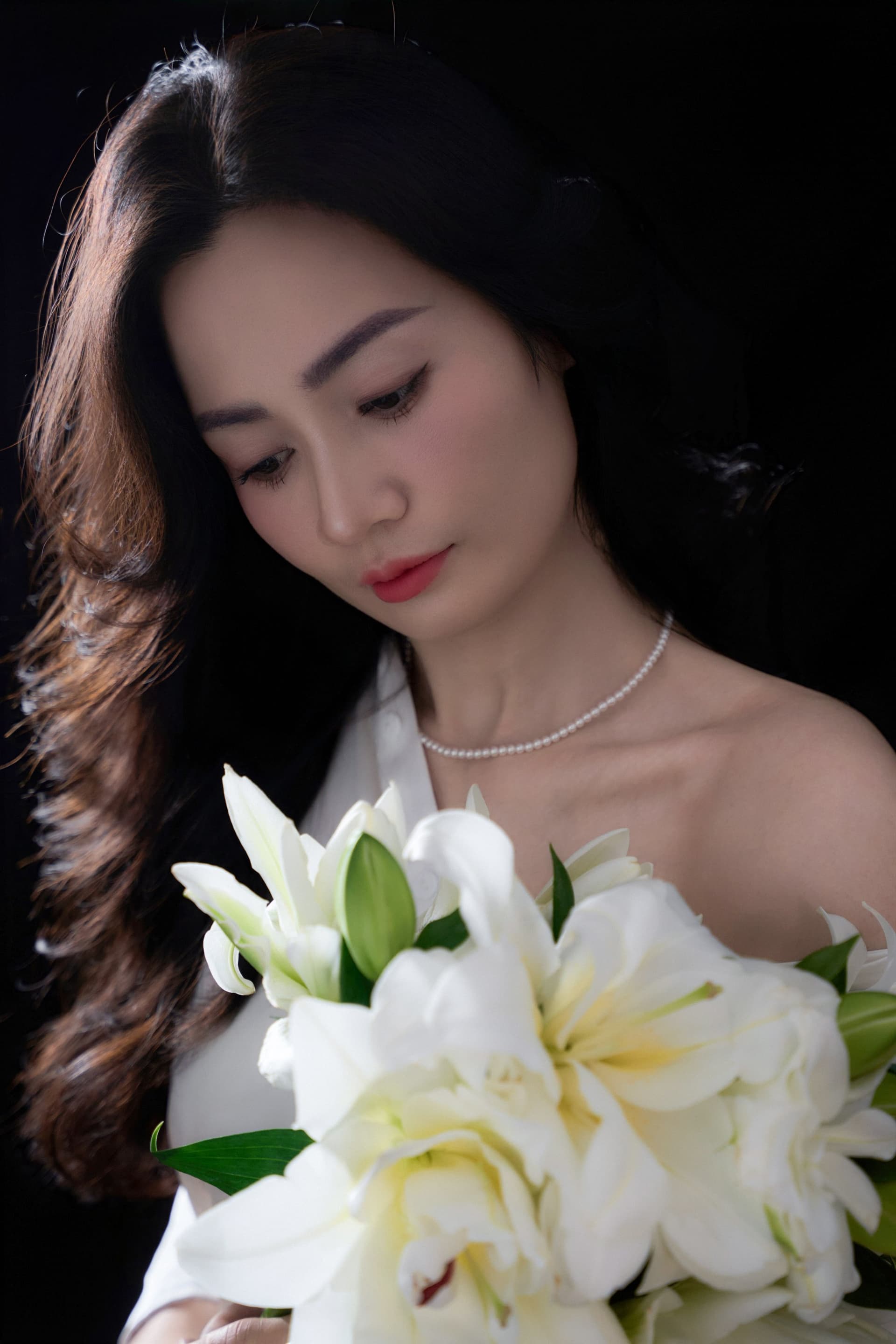 Cận cảnh gương mặt chị Phương Thủy nhìn xuống dưới đầy sâu lắng bên những đóa hoa trắng