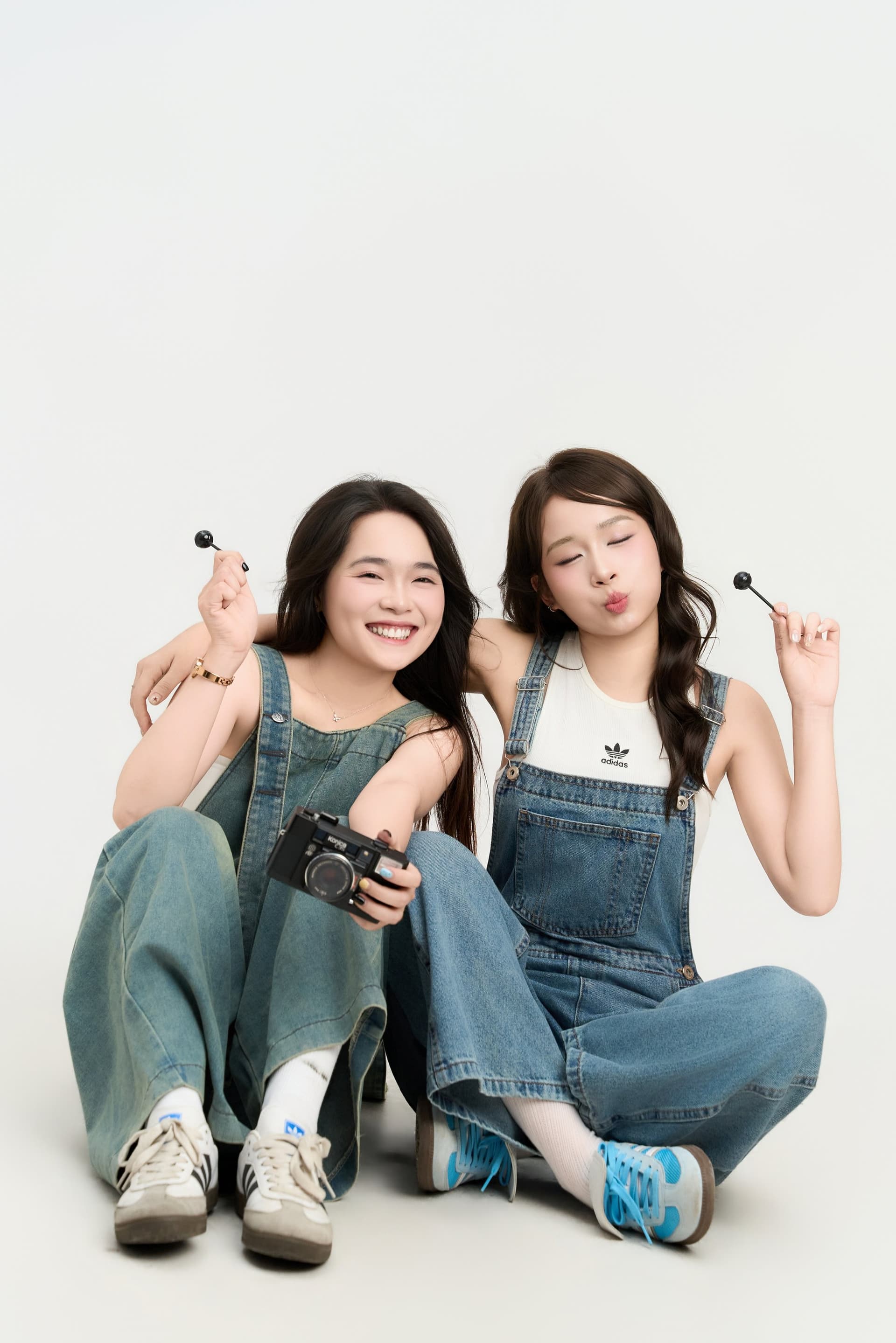 Hai cô gái Đậu Thảo Nhi và người bạn thân cùng ngồi trên sàn studio, cùng cười lớn rạng rỡ và tự nhiên