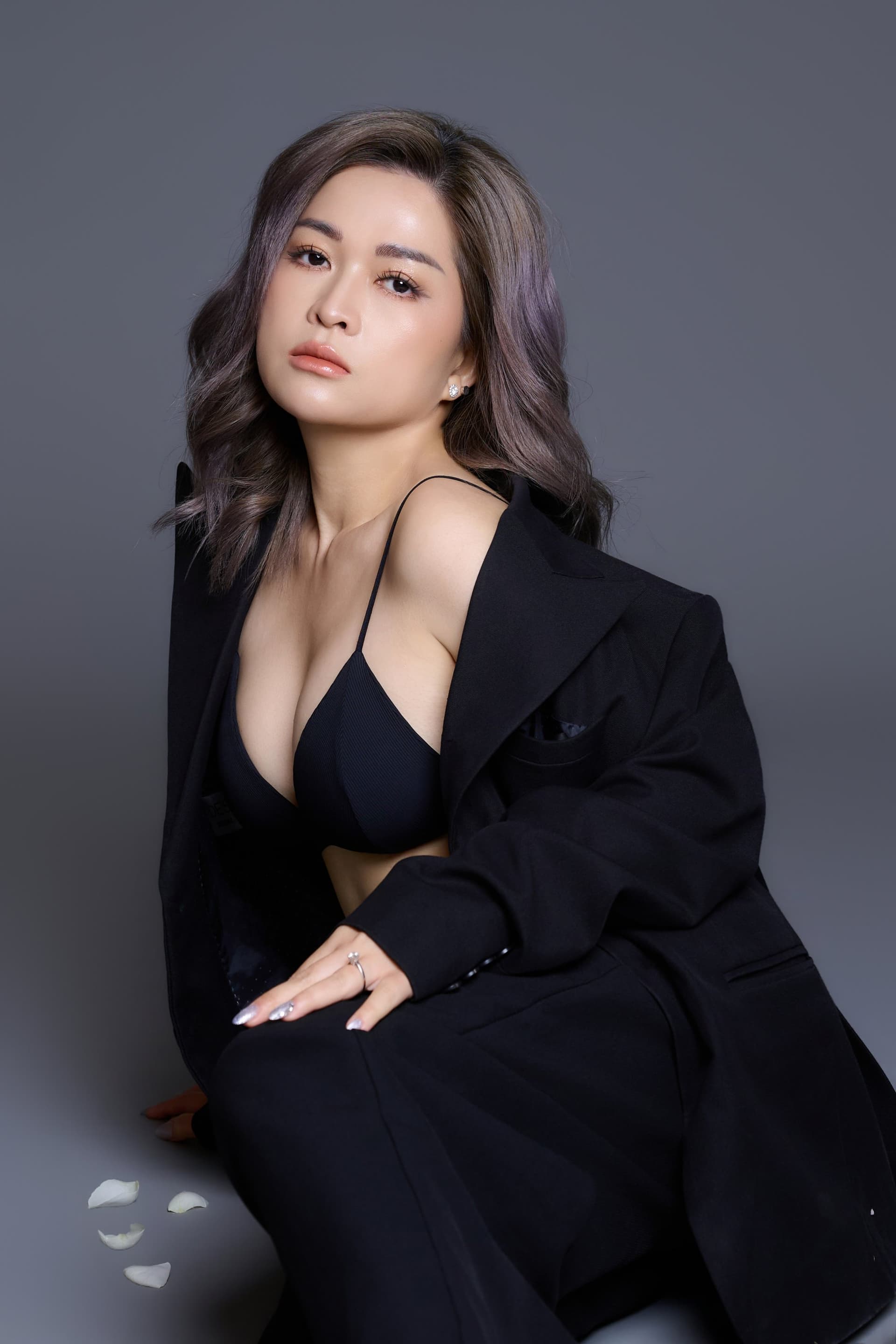 Người phụ nữ ngồi trong suit hở, gương mặt nghiêng nhìn xuống — khoảnh khắc nhận ra mình đã quen chờ quá lâu