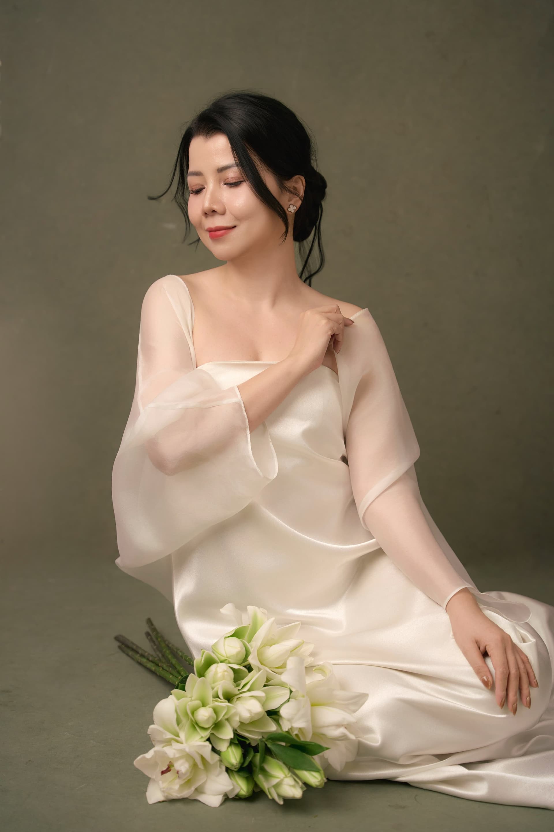 Chị Thanh Nhài trong tà áo dài lụa trắng, đứng nghiêng người nhìn xuống đầy suy tư tĩnh lặng