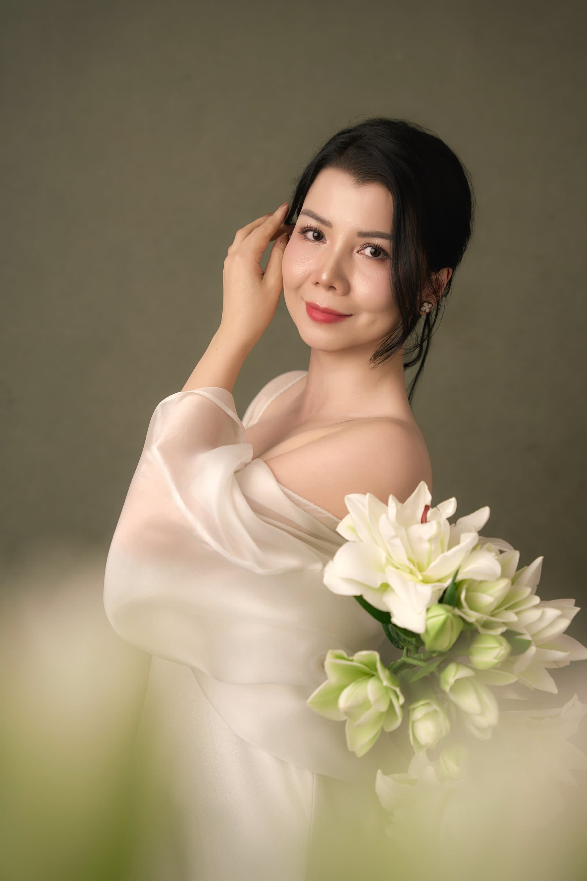 Chân dung tươi tắn của chị Thanh Nhài với nụ cười hiền hậu, tay nâng đóa hoa ly nở rộ đầy tự nhiên