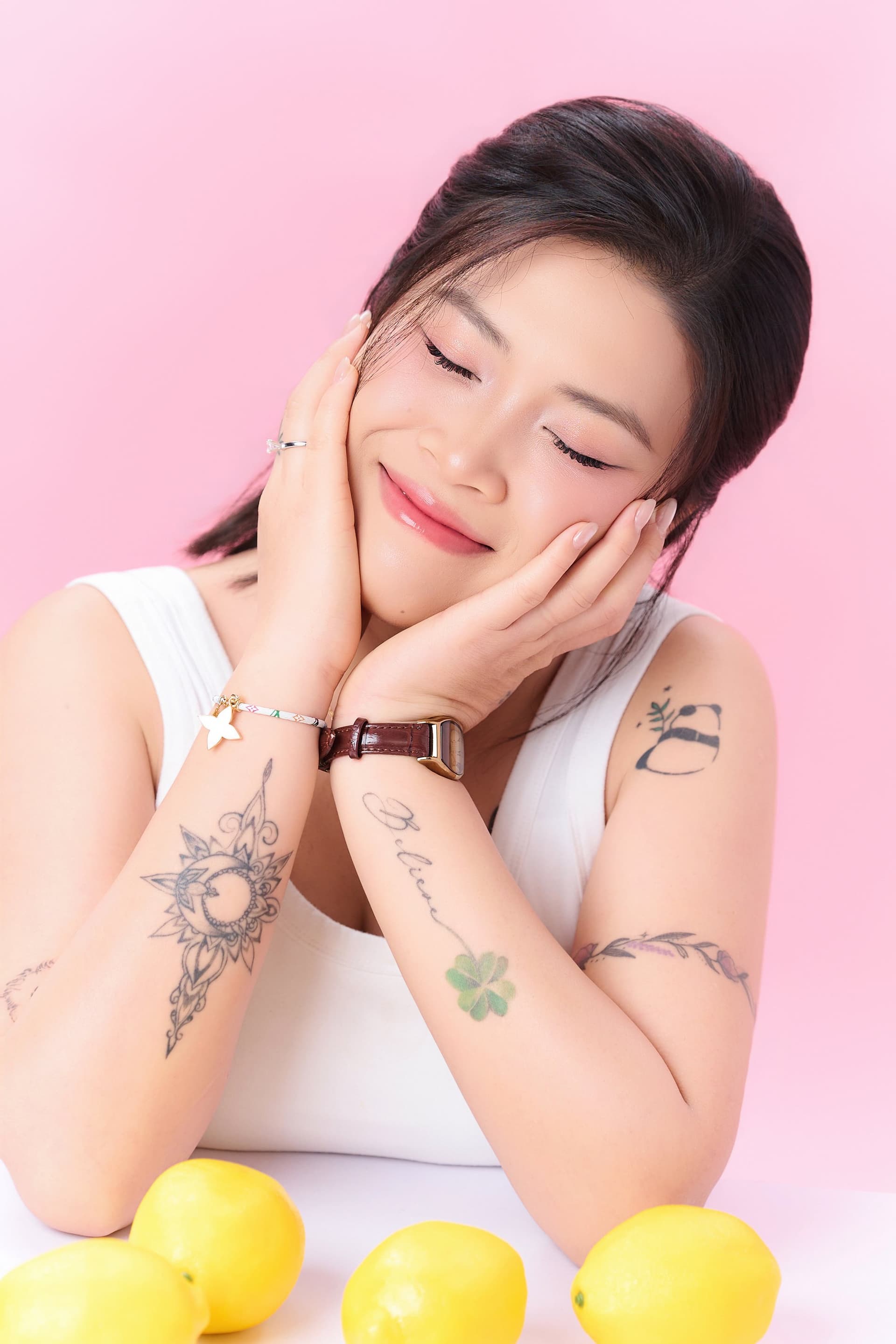 Khoảnh khắc Ngọc Thơ nhắm mắt cười bình yên, hai tay ôm má đầy thư thái trước phông nền hồng ngọt ngào