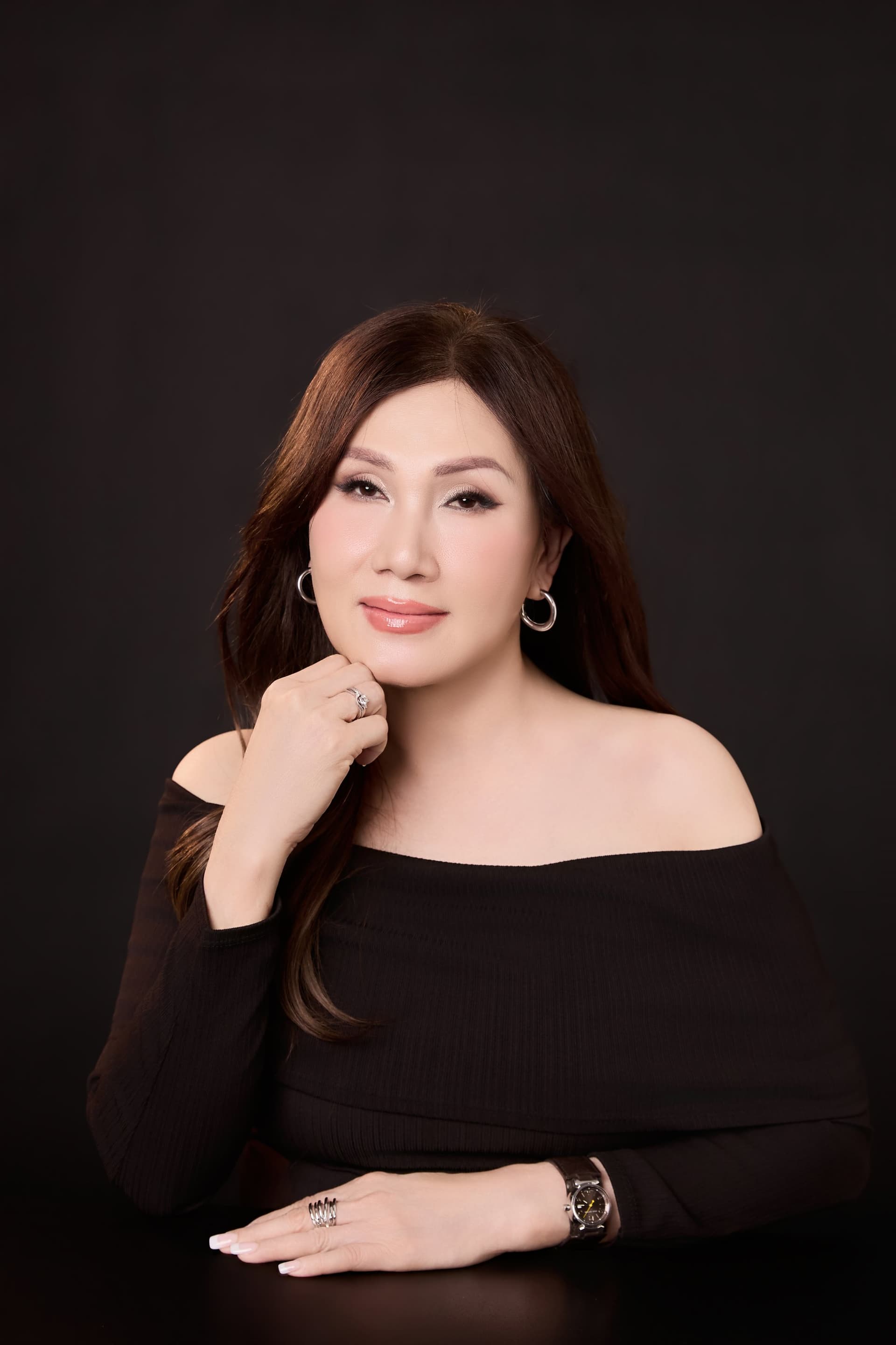 Mẹ mặc áo trễ vai đen sang trọng nở nụ cười tươi tắn nét mặt đầy trẻ trung cuốn hút